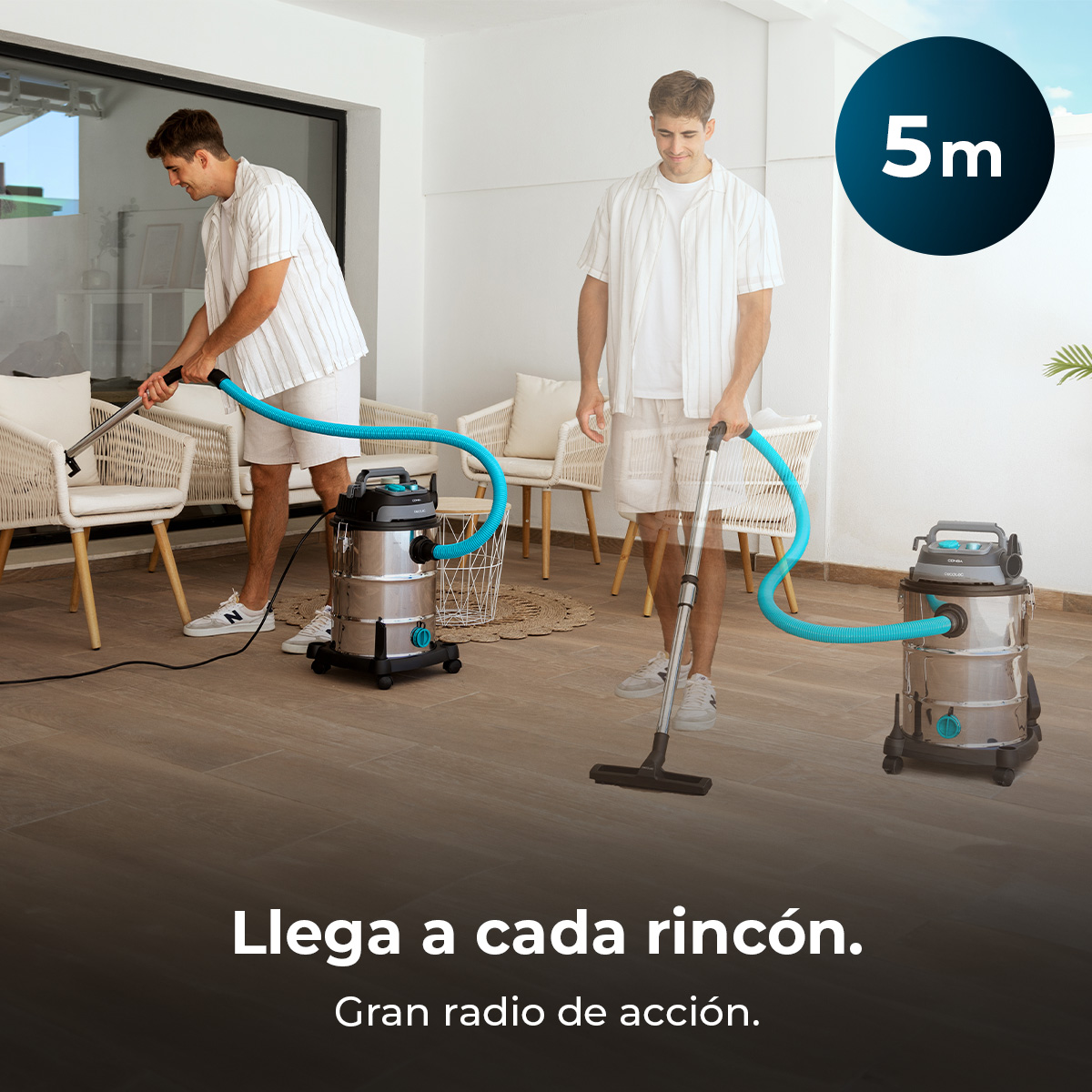 Un hombre usa una gran aspiradora de acero inoxidable con una manguera azul larga en un balcón.