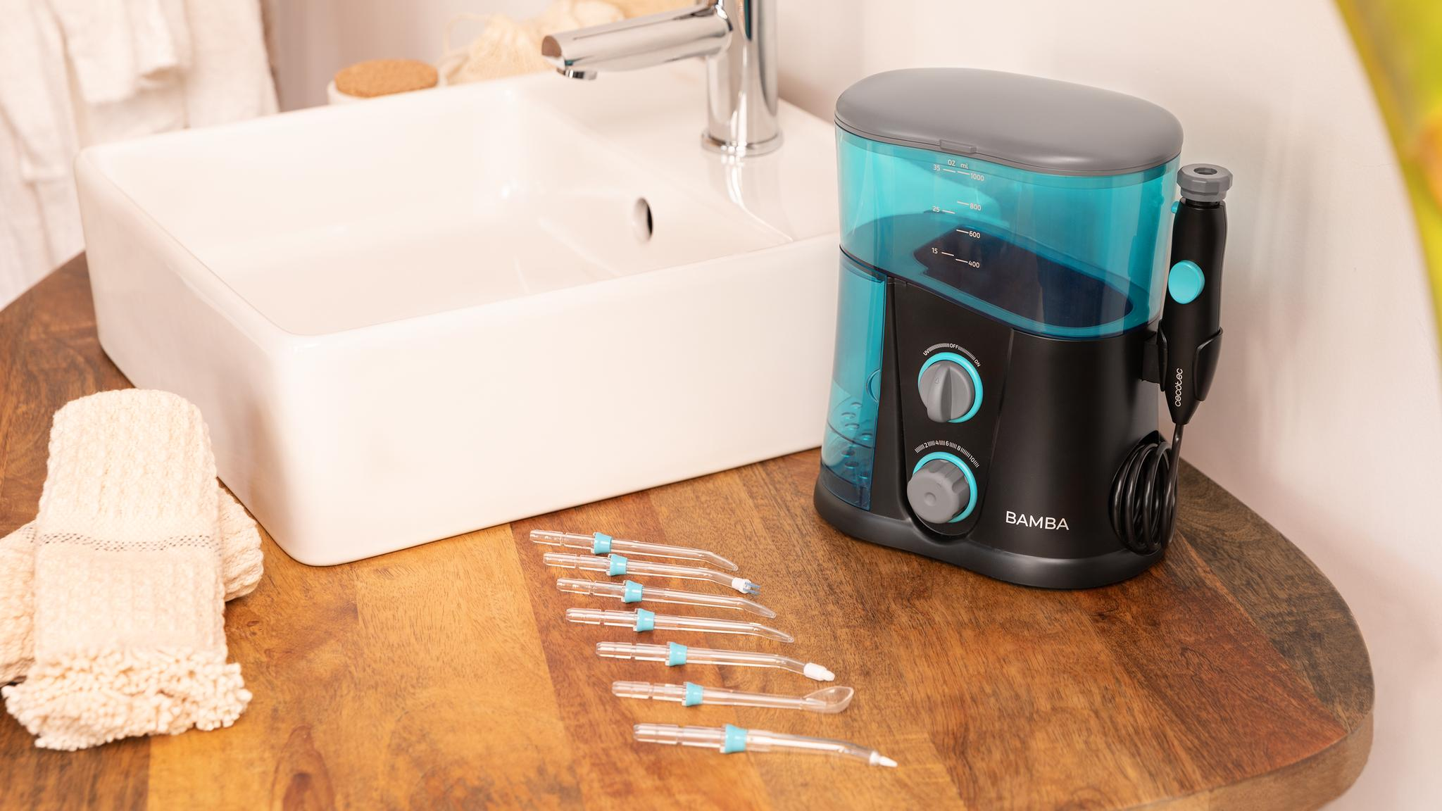 Un irrigador bucal negro y azul con boquillas y un lavabo blanco en un mueble de madera.