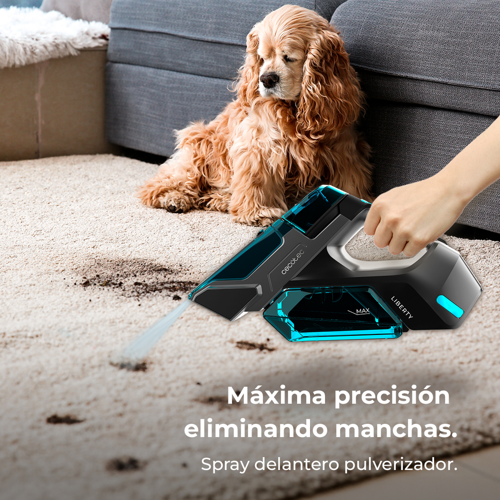Una mano usa un limpiador portátil para rociar agua en una alfombra manchada, con un perro cerca.