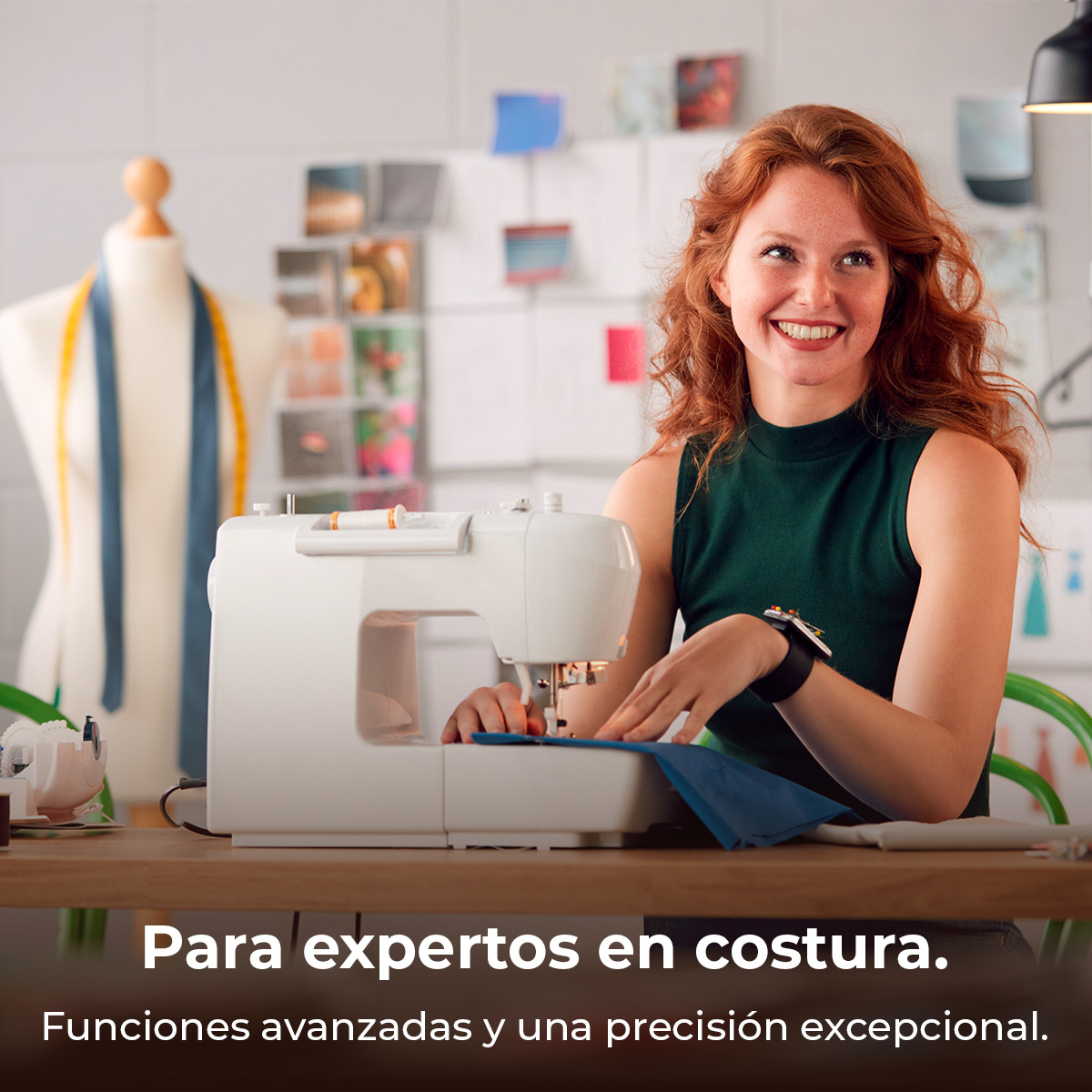 Mujer pelirroja sonríe y cose con una máquina de coser en un estudio.
