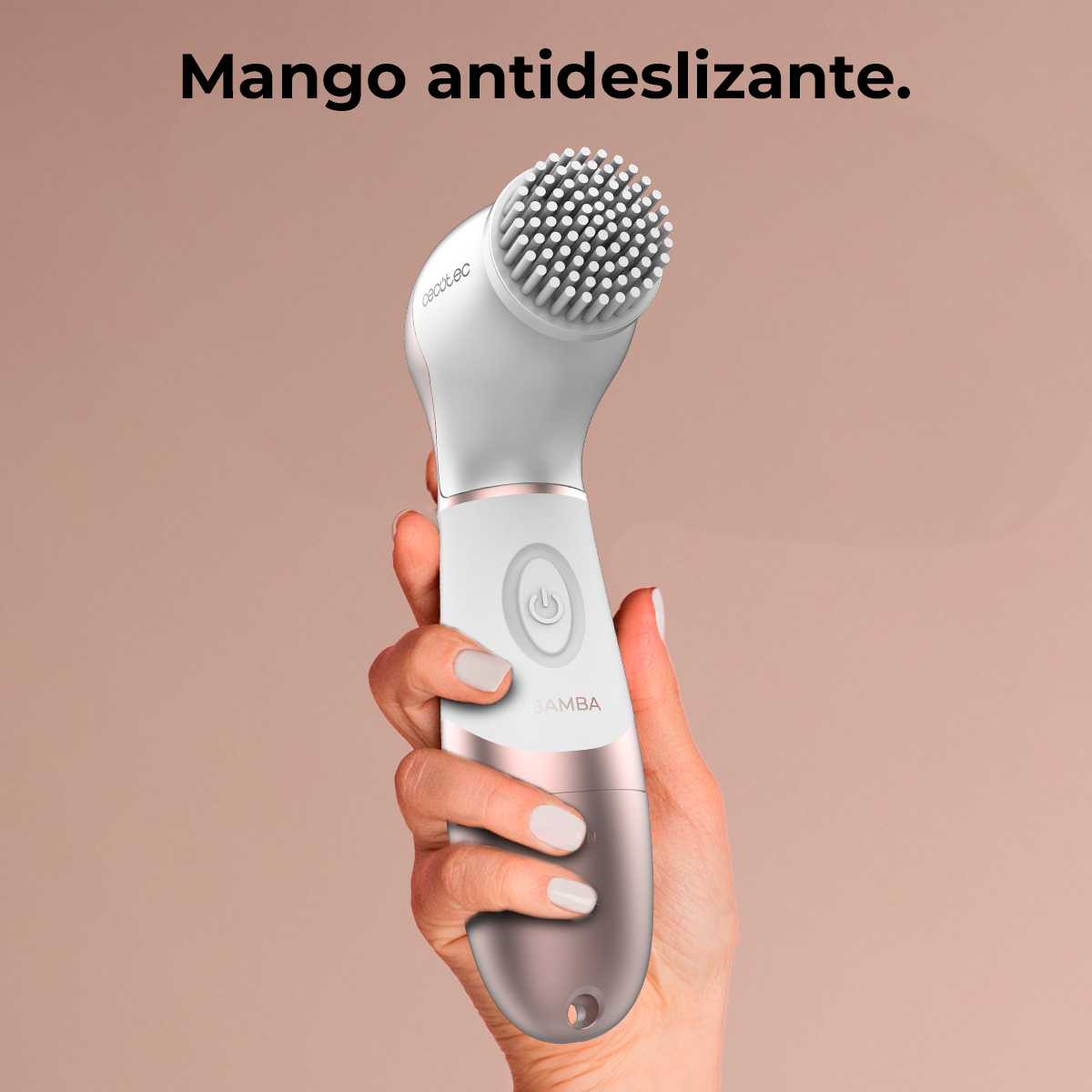 Una mano sosteniendo un cepillo facial blanco y oro rosa sobre un fondo neutro.