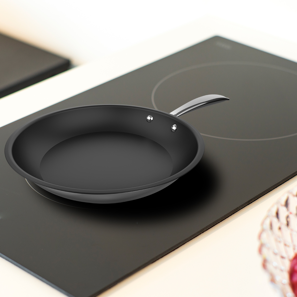 Una sartén negra con mango plateado descansa sobre una placa de inducción en una cocina moderna.