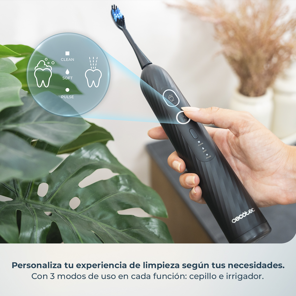 Una mano sostiene un cepillo eléctrico negro con un gráfico azul que destaca los modos clean, soft y pulse.