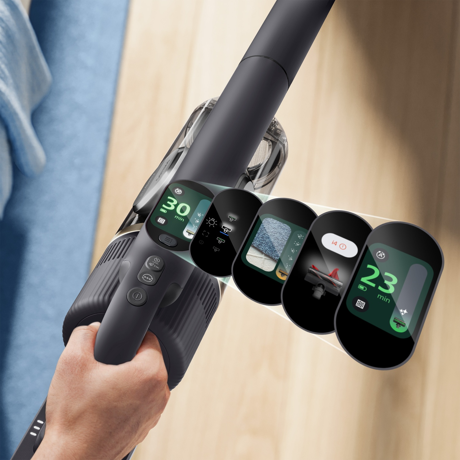 Close-up of a cordless vacuum handle showing digital display screens with battery life and settings over a wooden floor.