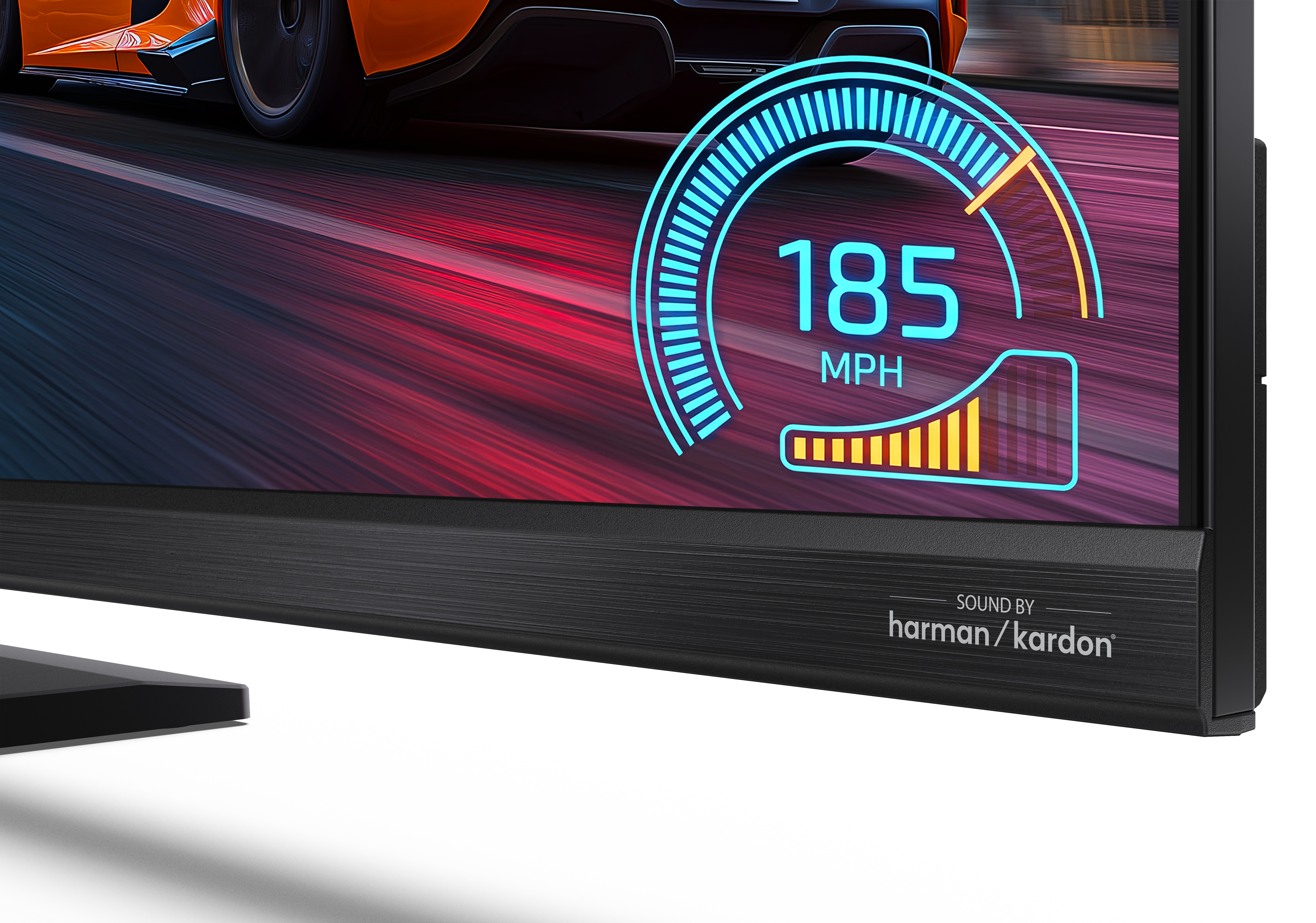 Ekran pokazuje grę wyścigową z licznikiem 185 MPH, na dole napis Sound by Harman Kardon.
