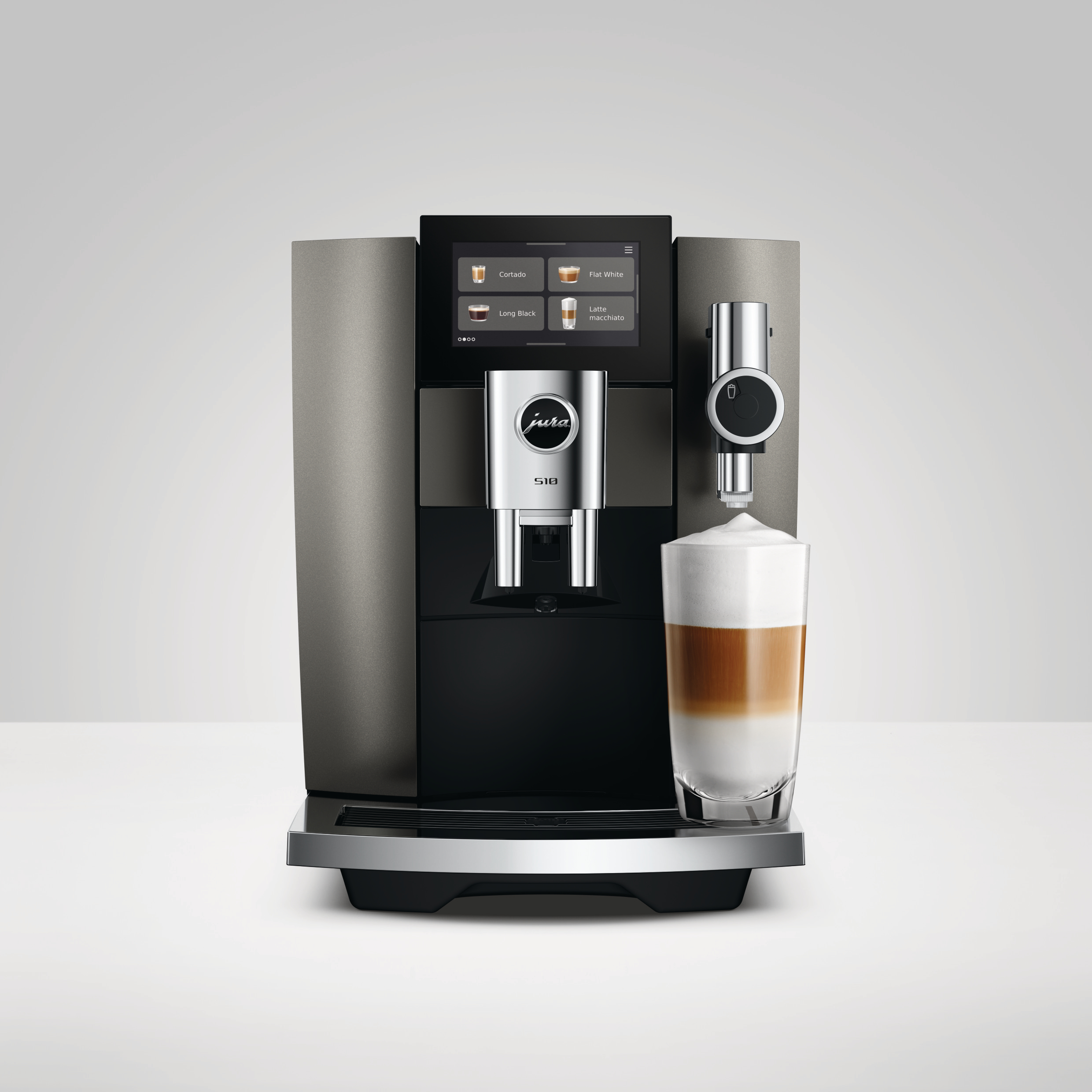 Eine moderne graue und schwarze Jura S10 Kaffeemaschine, die einen Latte Macchiato füllt.
