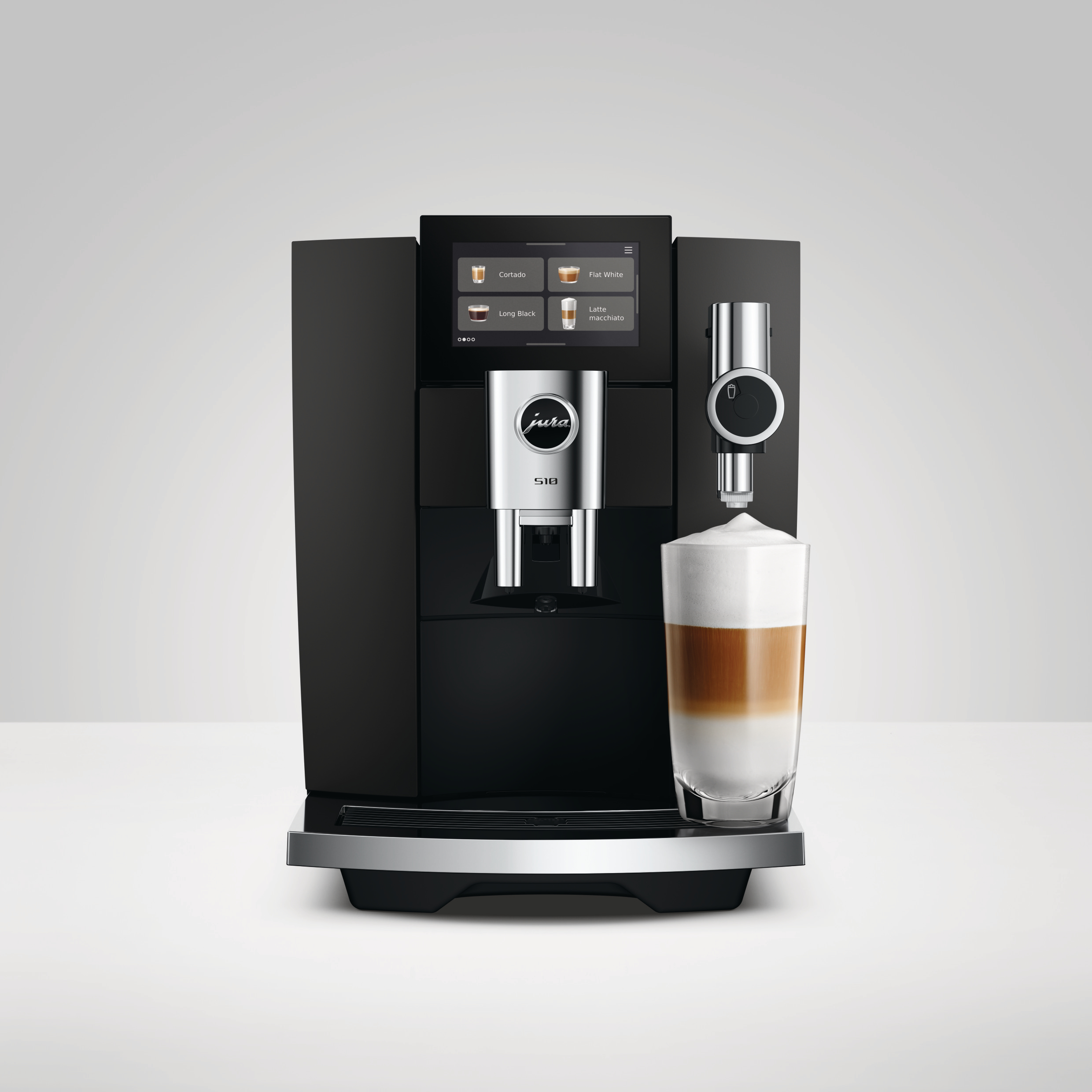 Moderne schwarze Jura S10 Kaffeevollautomat mit einem frisch zubereiteten Latte Macchiato in einem Glas.