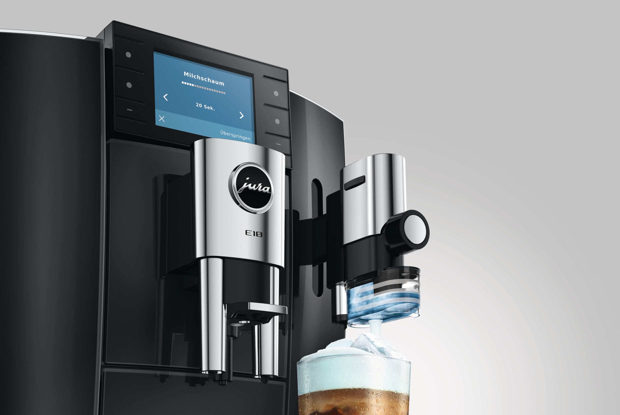Moderne schwarze Jura E8 Kaffeemaschine mit Display zeigt Milchschaum-Zubereitung für ein Glas Eiskaffee.