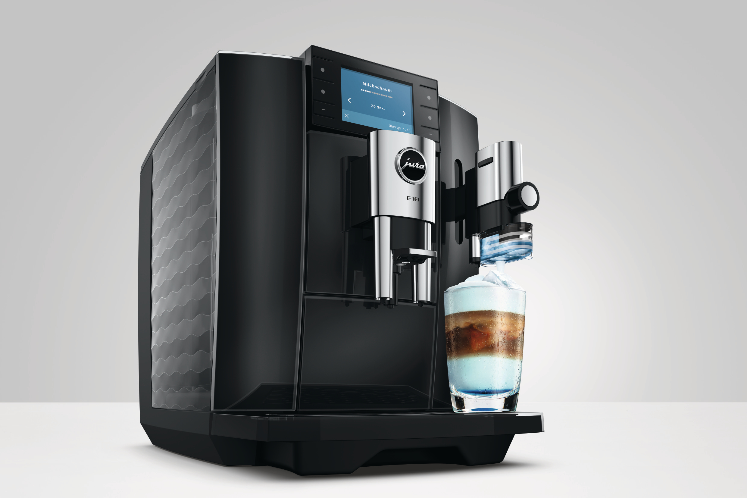 Schwarzer Kaffeeautomat Jura E10 mit Display, der ein kaltes Getränk in ein Glas füllt.