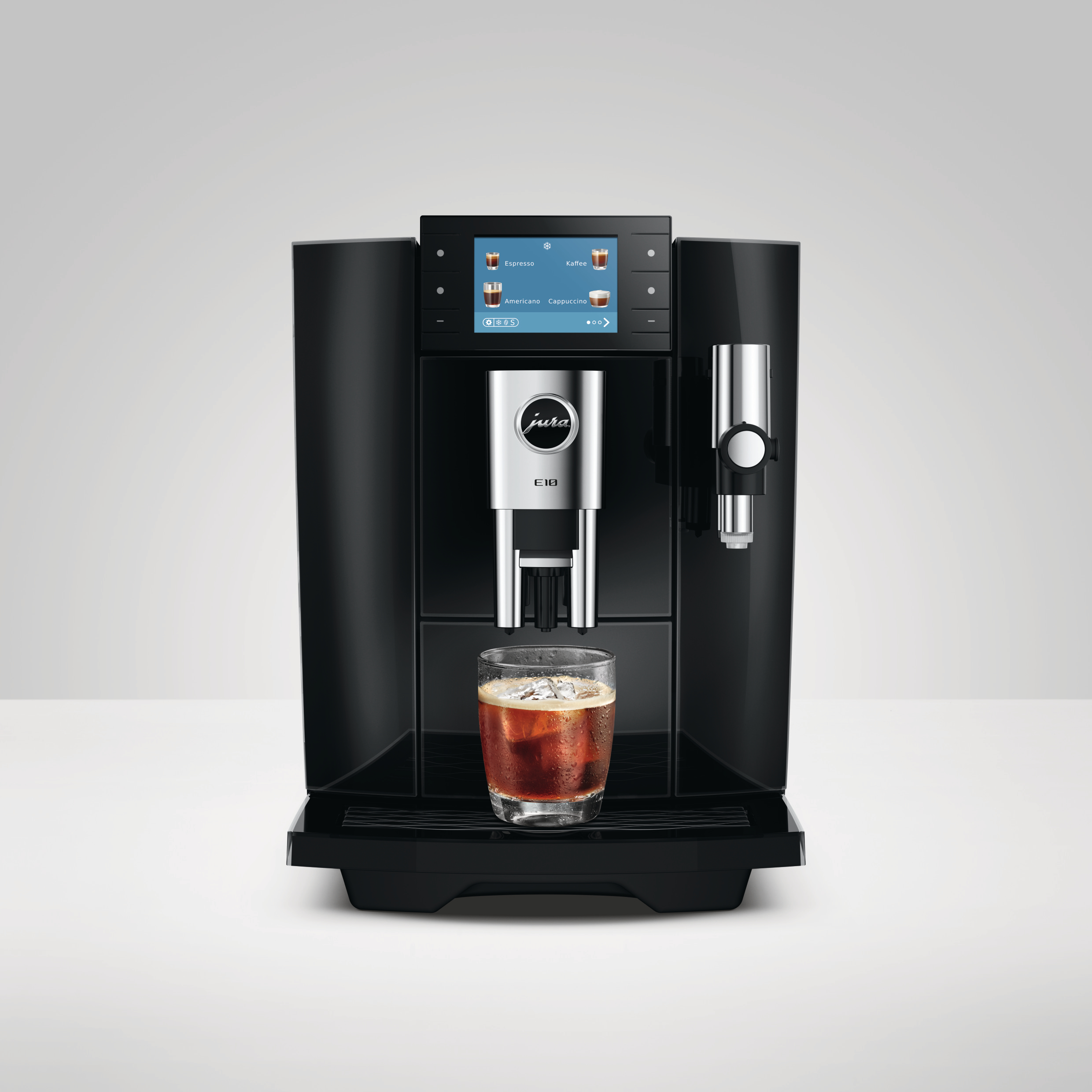 Moderne schwarze Jura E10 Kaffeemaschine auf einem Tisch mit einem Glas Eiskaffee.