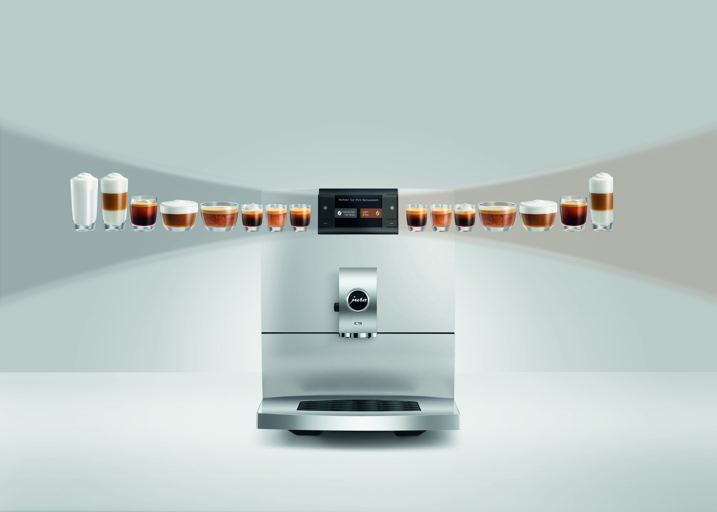 Eine silberne Jura C9 Kaffeemaschine mit einer Reihe verschiedener Kaffeespezialitäten in Gläsern darüber.