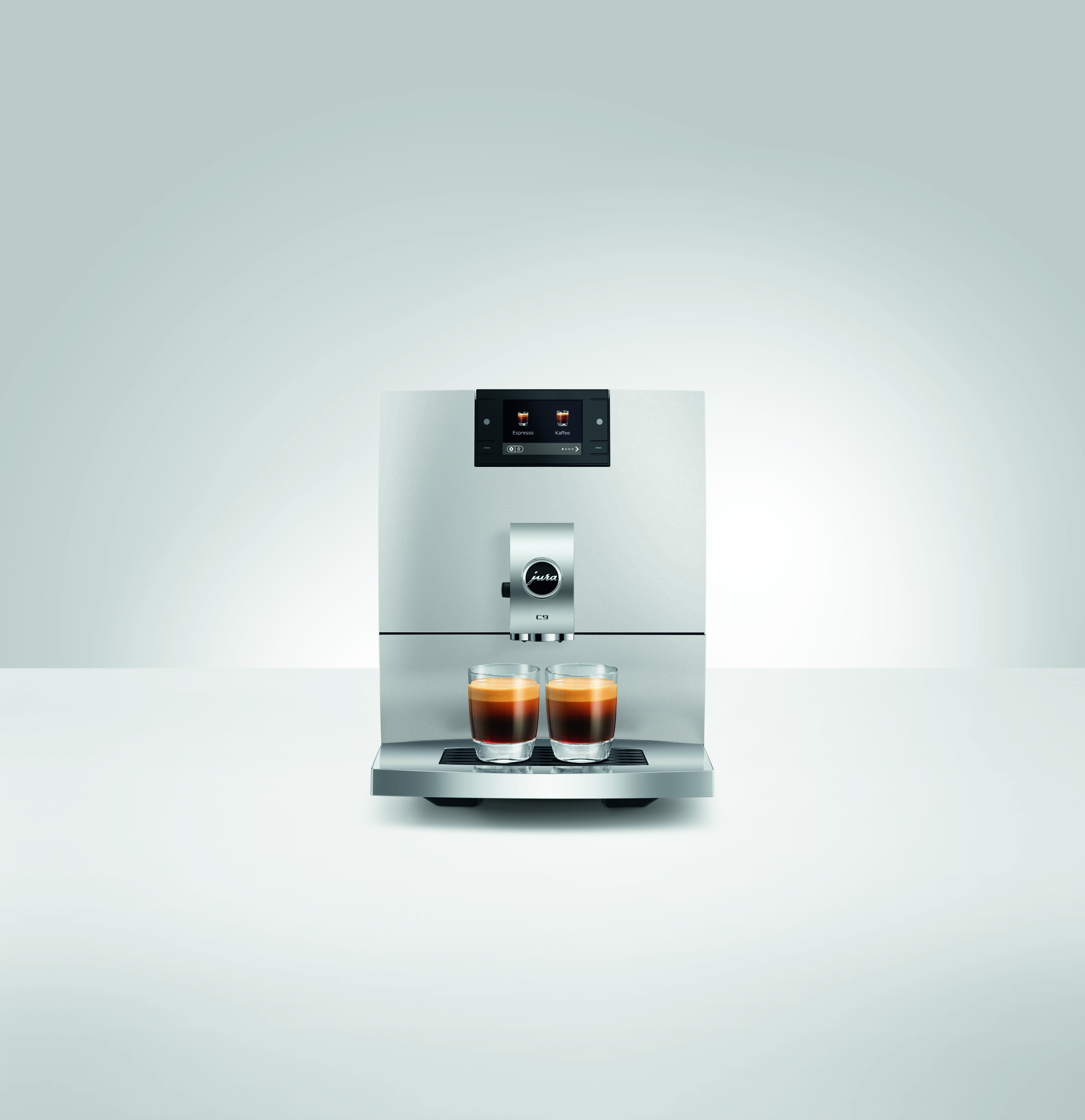 Eine silberne Jura G9 Kaffeemaschine steht auf einer weißen Oberfläche und füllt zwei Espressotassen.