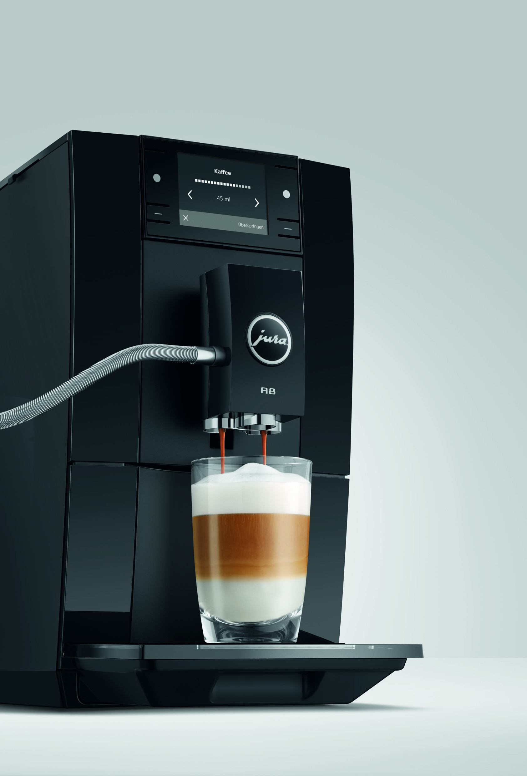 Eine schwarze Jura A8 Kaffeemaschine füllt ein geschichtetes Latte-Macchiato-Glas.