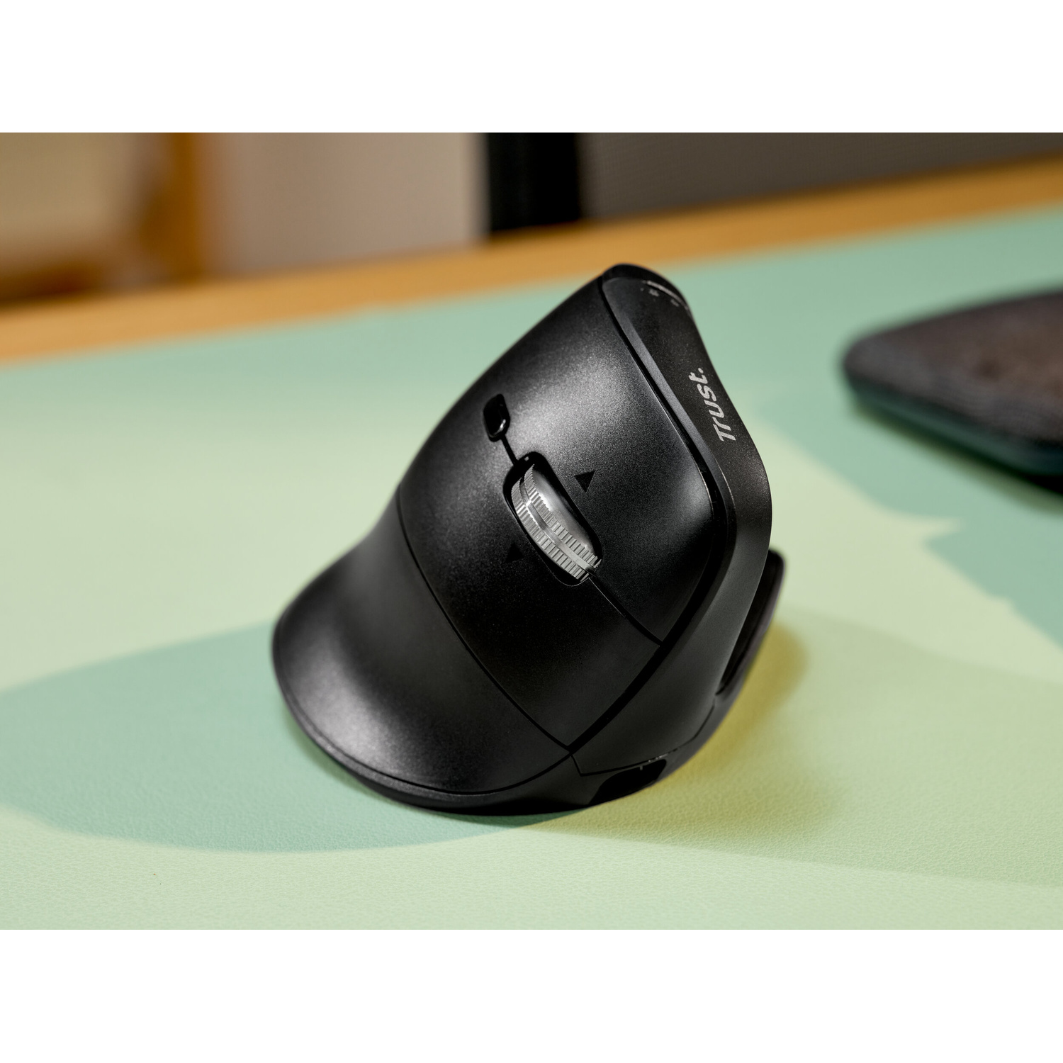 Mouse per computer verticale ergonomico nero su un tappetino verde menta.