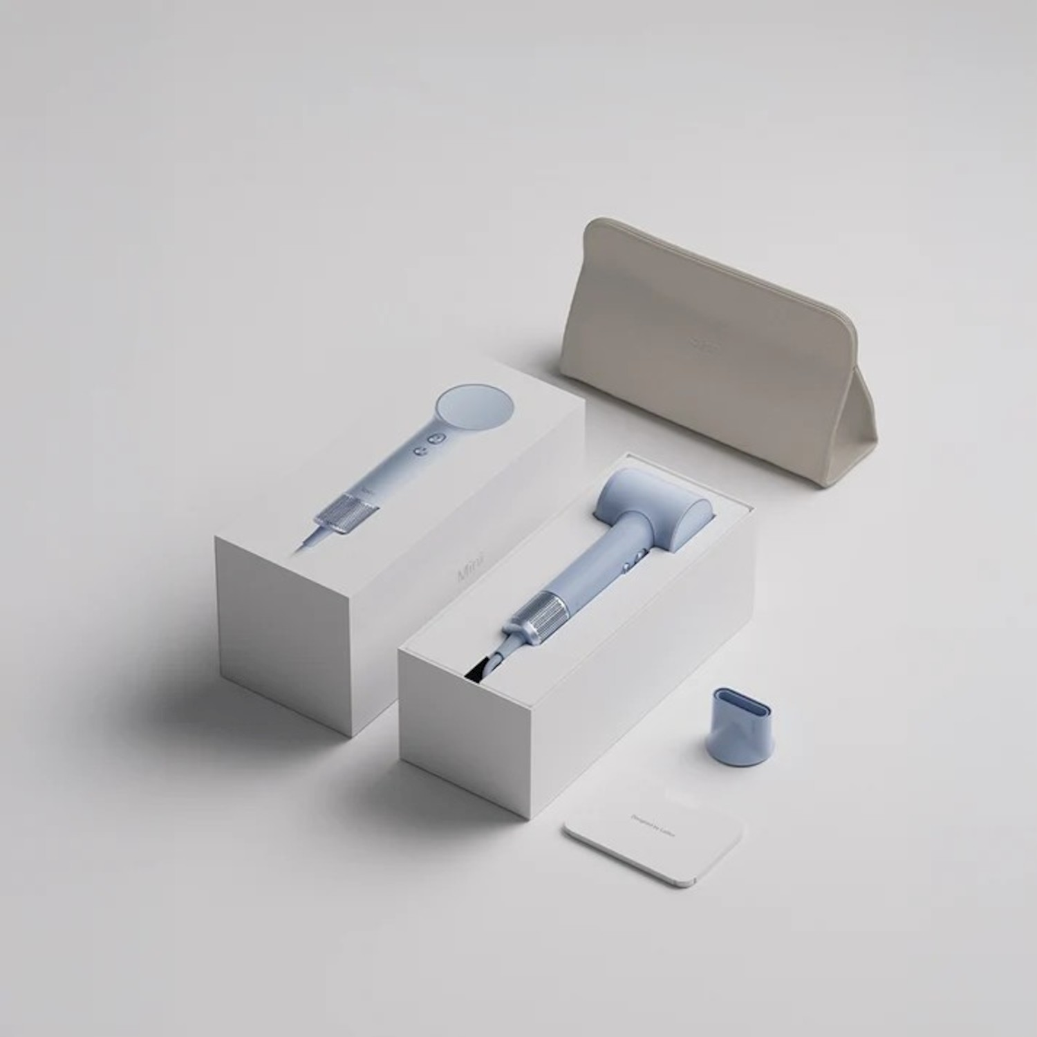 Un mini asciugacapelli blu con confezione, accessori e una custodia grigia su sfondo chiaro.