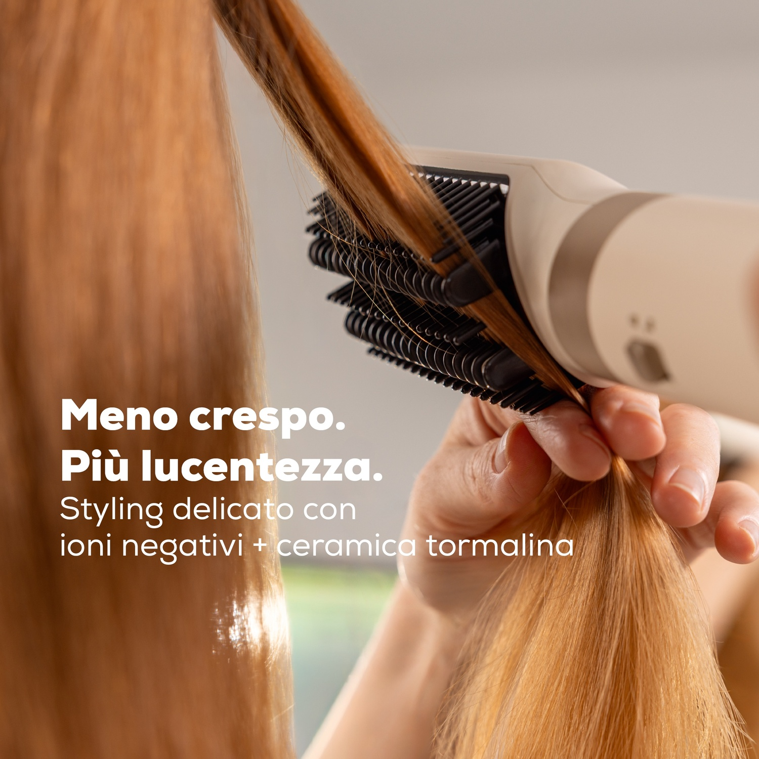 Una mano tiene una spazzola lisciante che liscia i capelli castani lunghi.