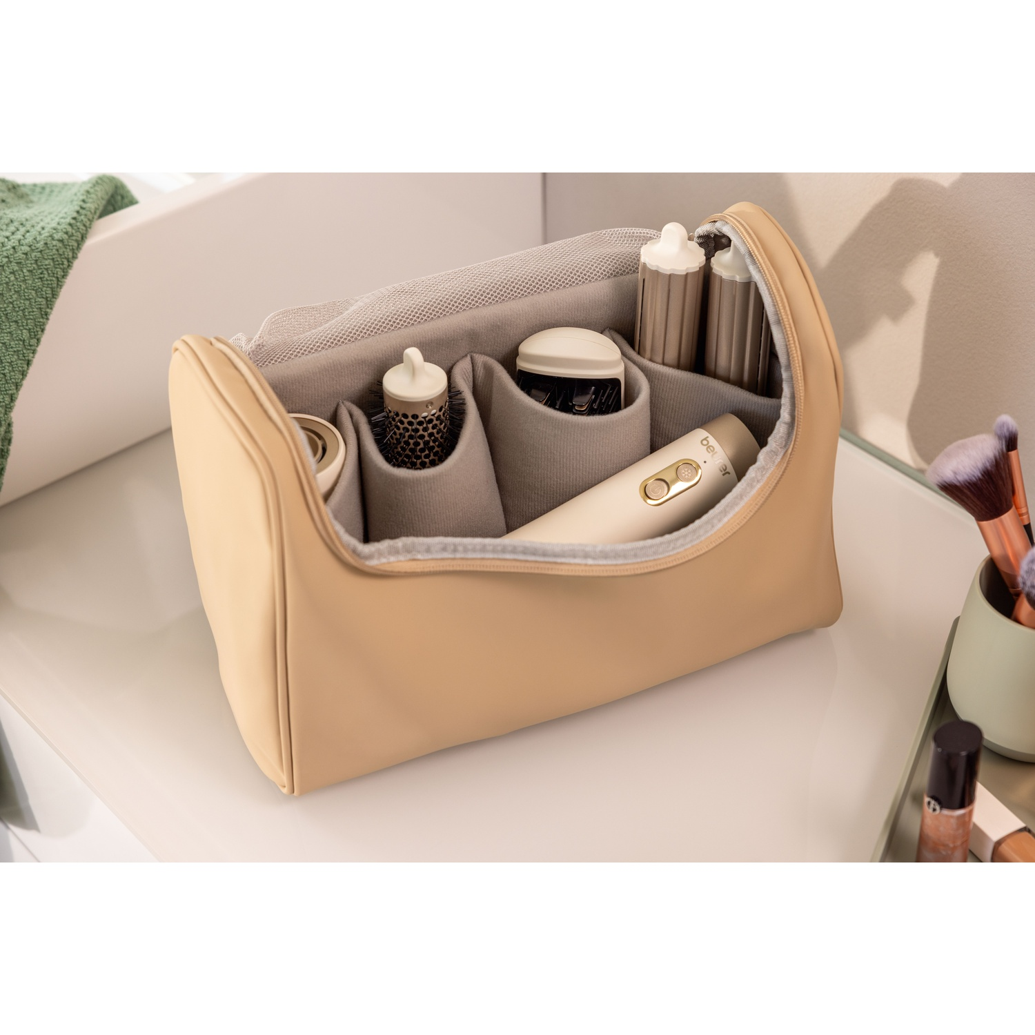 Una borsa cosmetica beige aperta con scomparti organizzati contiene strumenti per lo styling dei capelli.