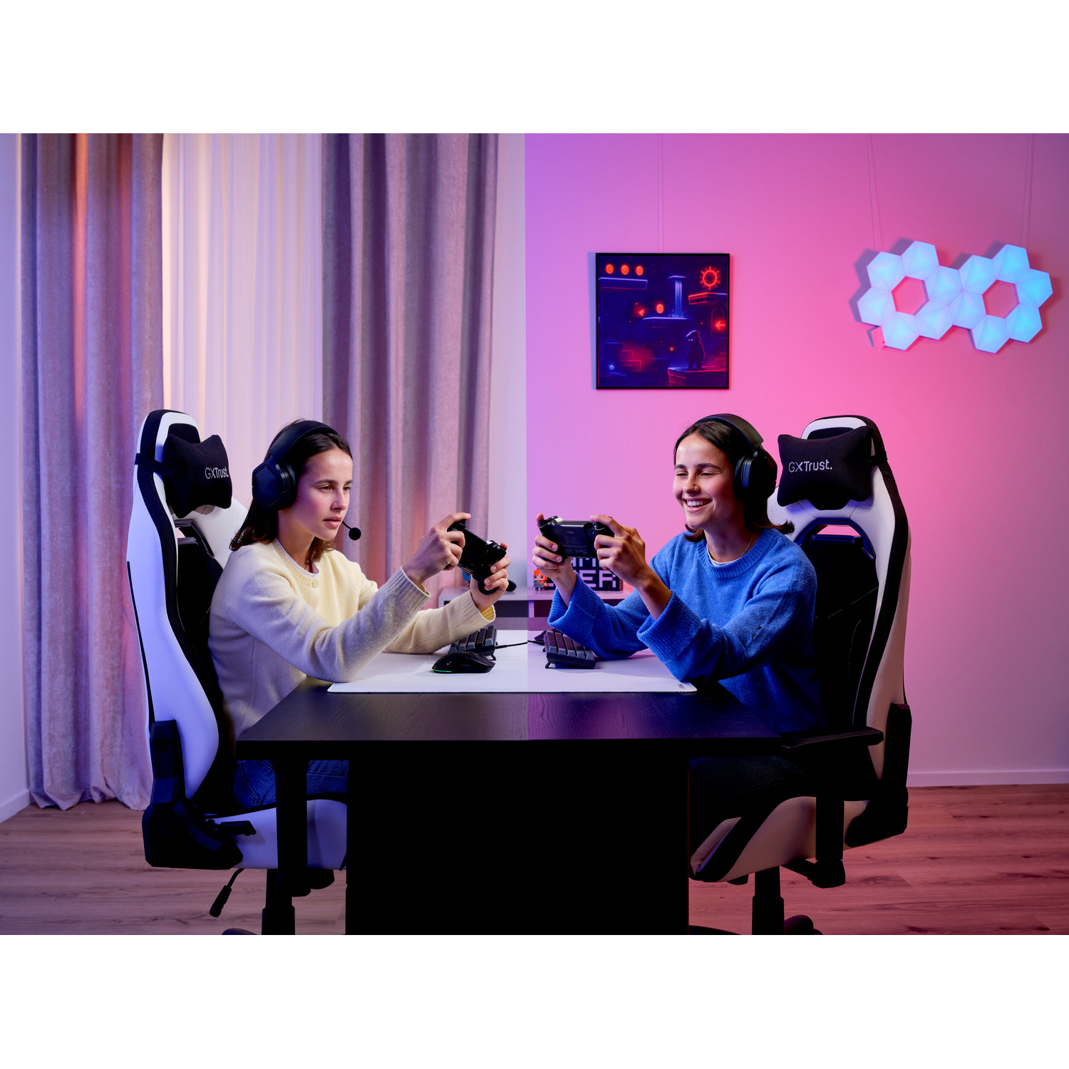 Due ragazze siedono su sedie da gioco a un tavolo e giocano ai videogiochi con i controller.