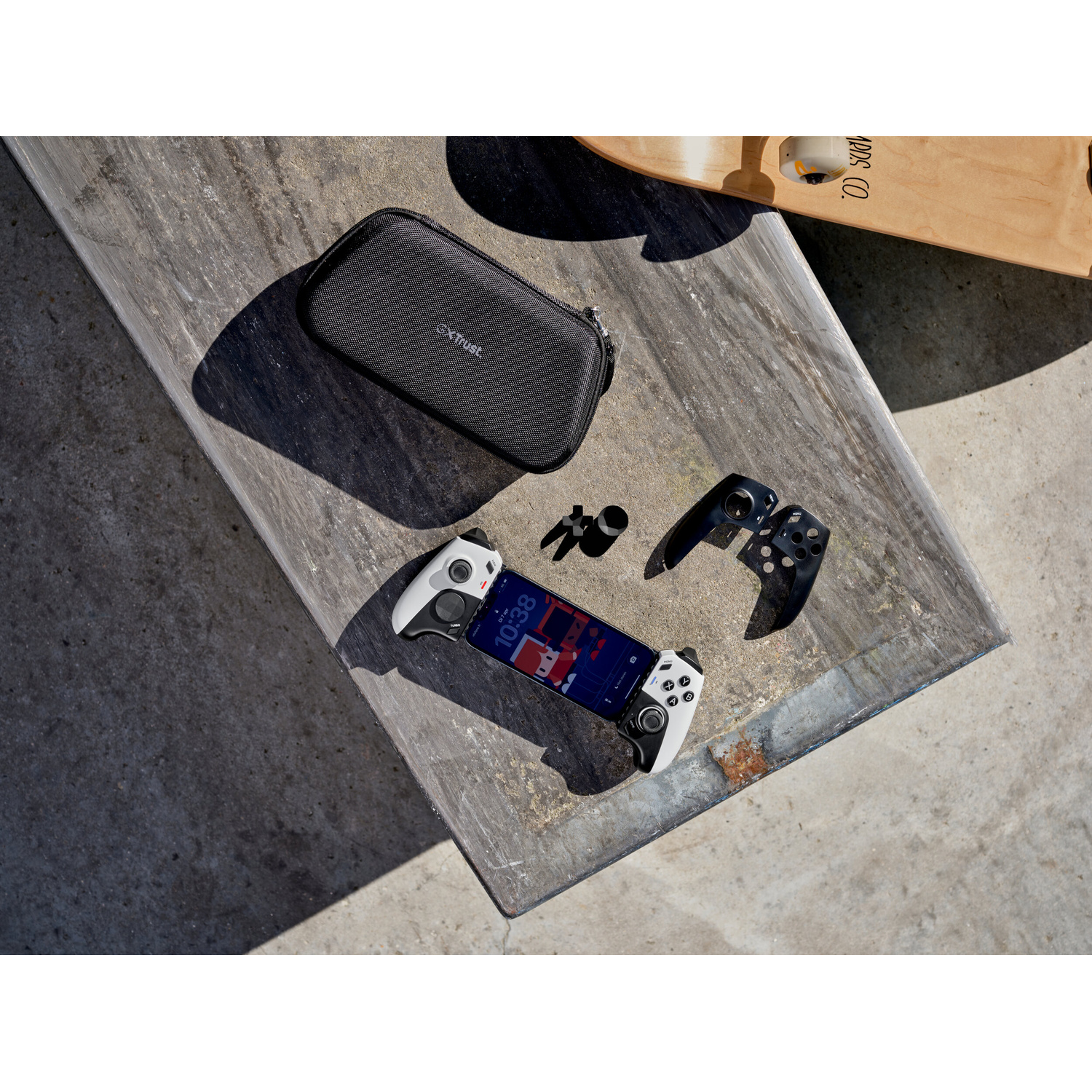 Uno smartphone con controller bianchi è su un tavolo di legno con una custodia nera e uno skateboard.