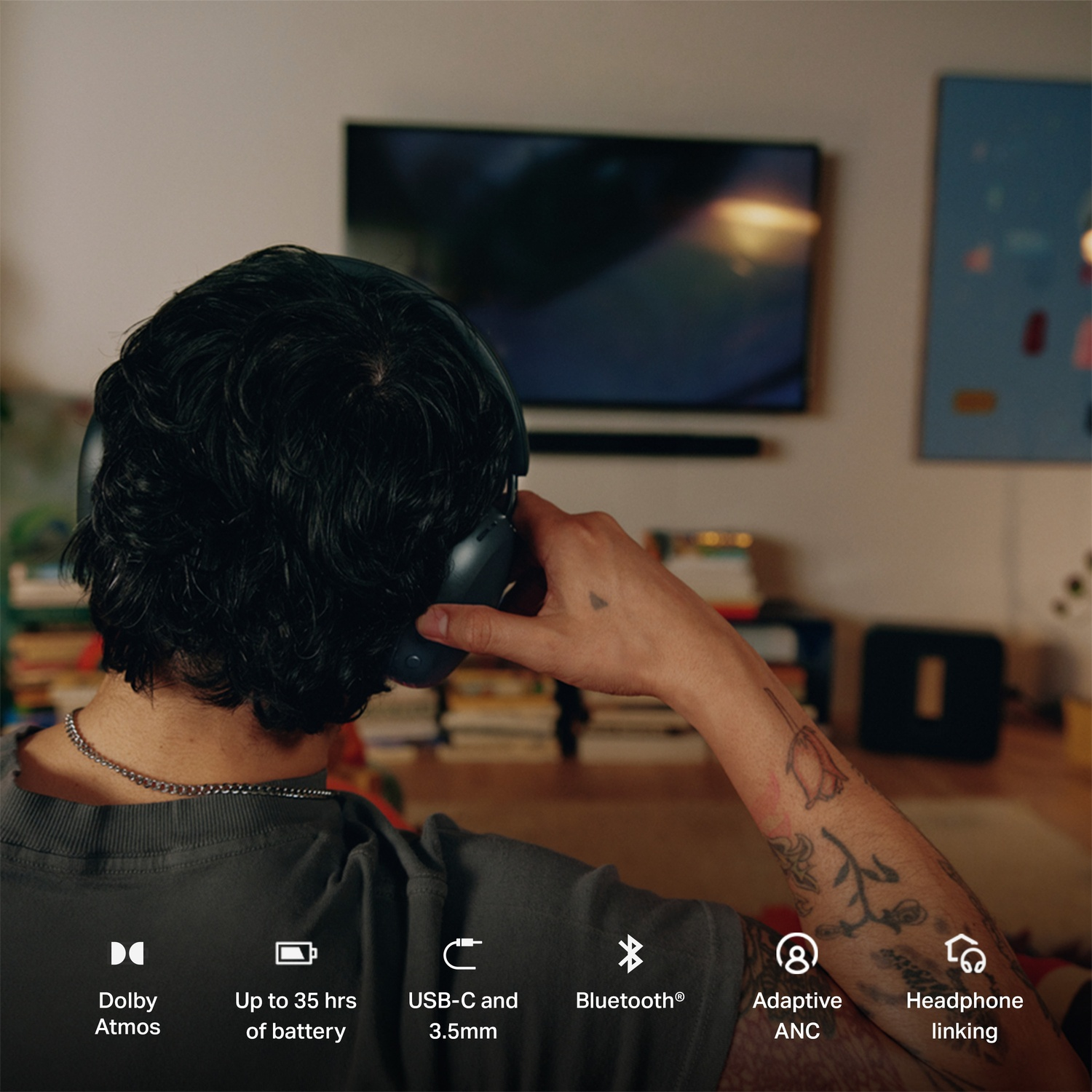 Persoon met koptelefoon van achteren gezien,kijkt tv, met iconen voor Dolby Atmos en batterijduur.