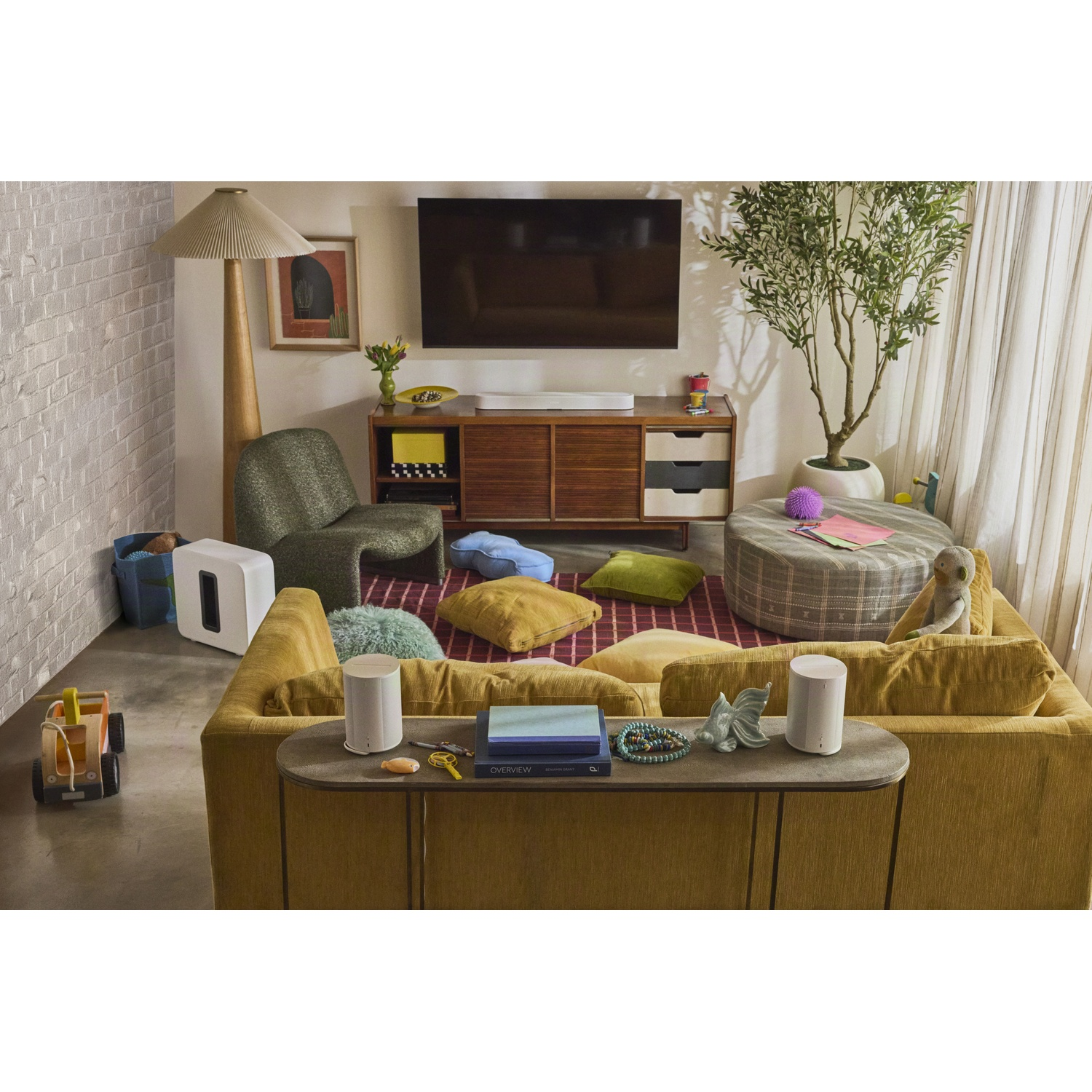 Salon chaleureux avec canapé jaune, télévision, plante et coussins.
