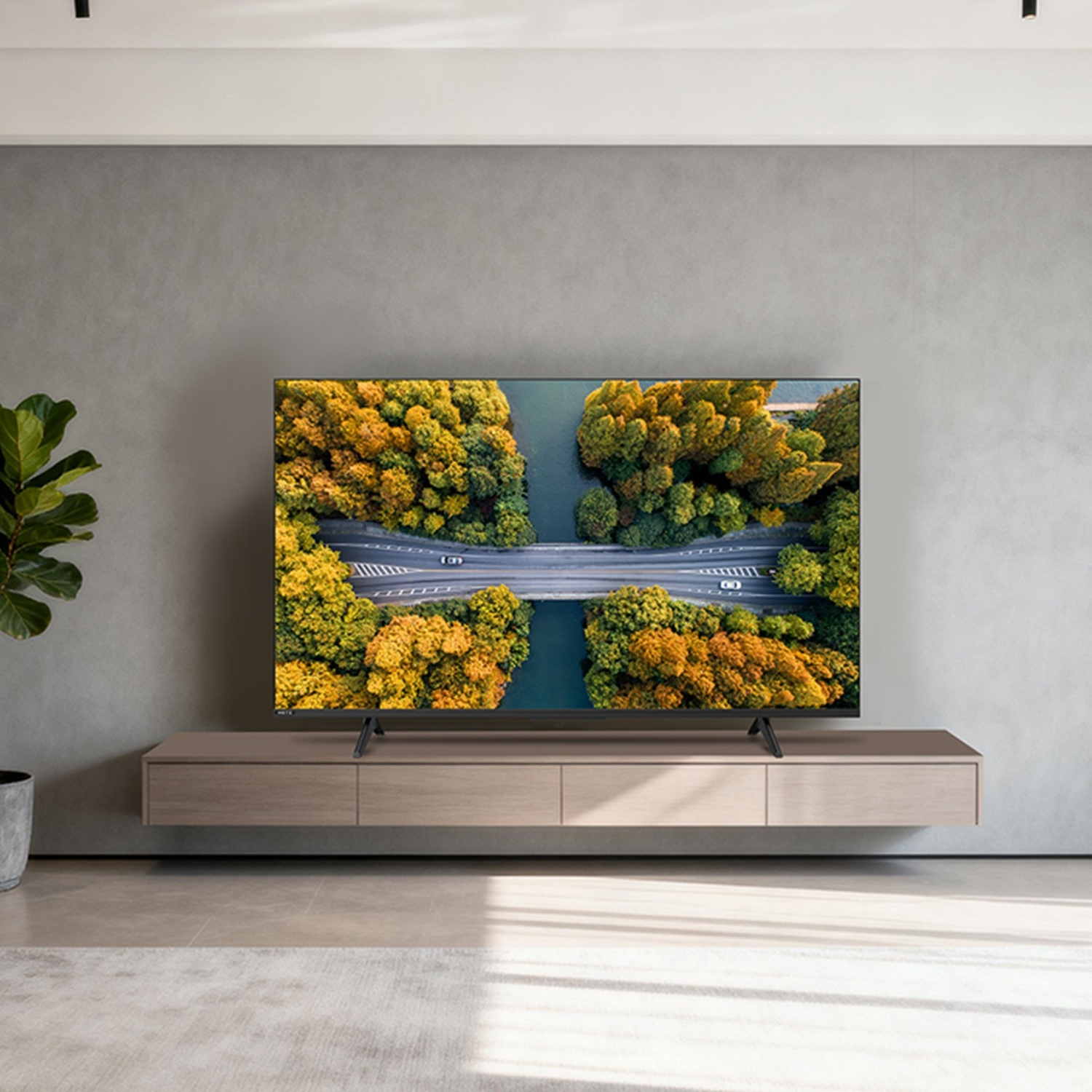 Una TV su un mobile multimediale moderno mostra una vista aerea autunnale di fiume e strada.