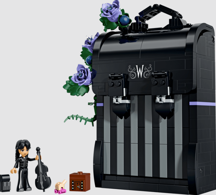 Lego-Set mit schwarzer Schachtel, blauen Blumen, Minifigur, Cello, Thing-Hand und Truhe vor hellem Hintergrund.