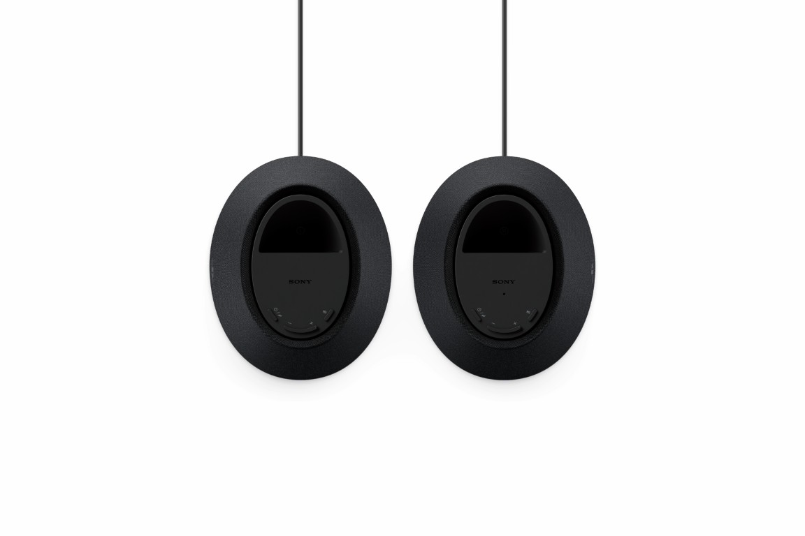 Dwa czarne głośniki konferencyjne Sony wiszą na pionowych kablach na białym tle.