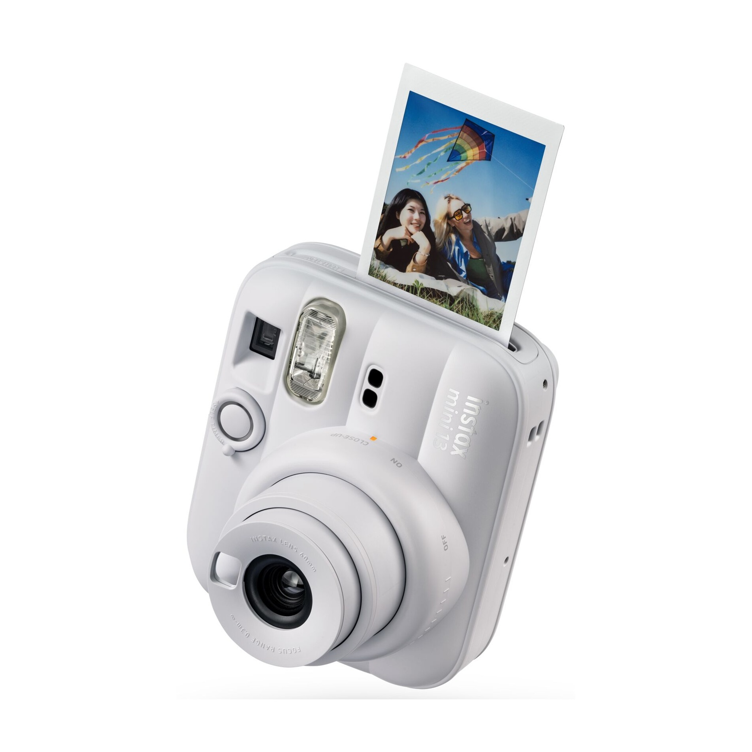 Fotocamera istantanea bianca con una foto espulsa che mostra due donne sorridenti con un aquilone.