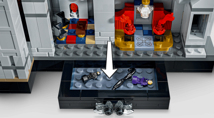 Draufsicht auf ein Lego-Schlossinnere mit Zimmern, Figuren und einer offenen Schublade mit kleinen Gegenständen.