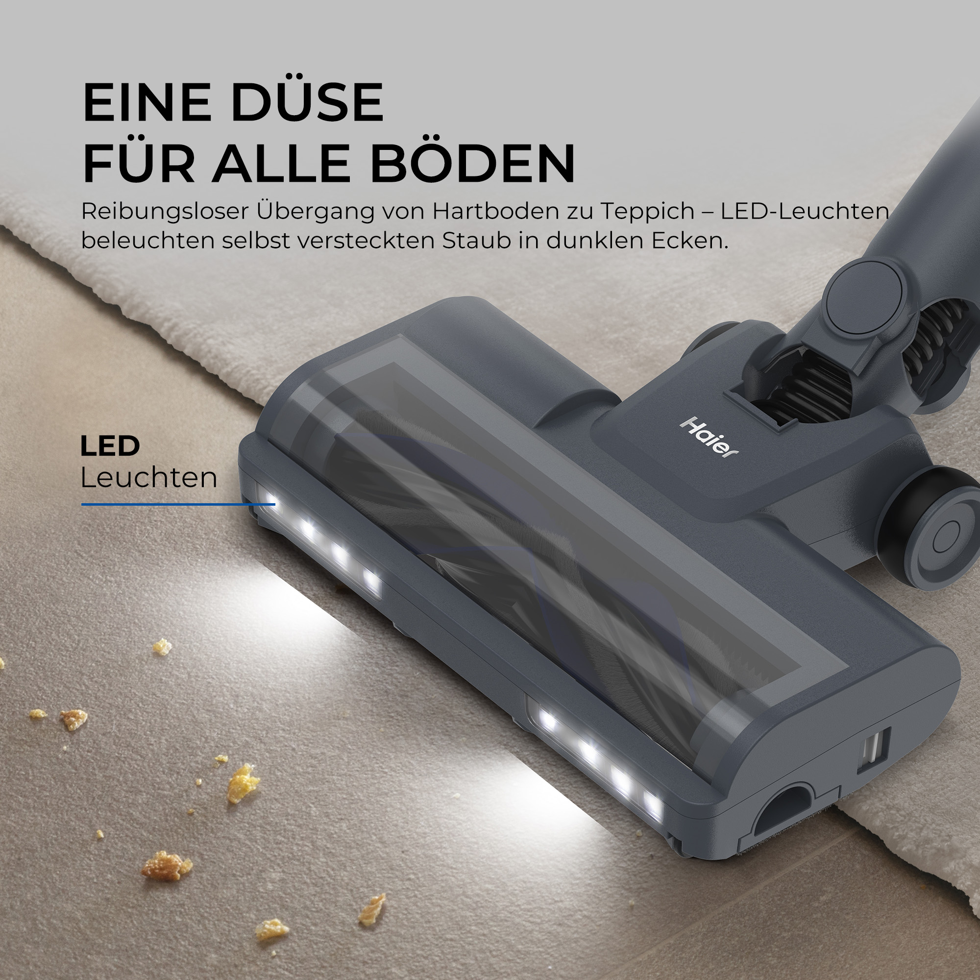 Ein grauer Haier Staubsaugerfuss mit hellen LED-Leuchten auf einem Holzboden mit Krümeln und Teppich.