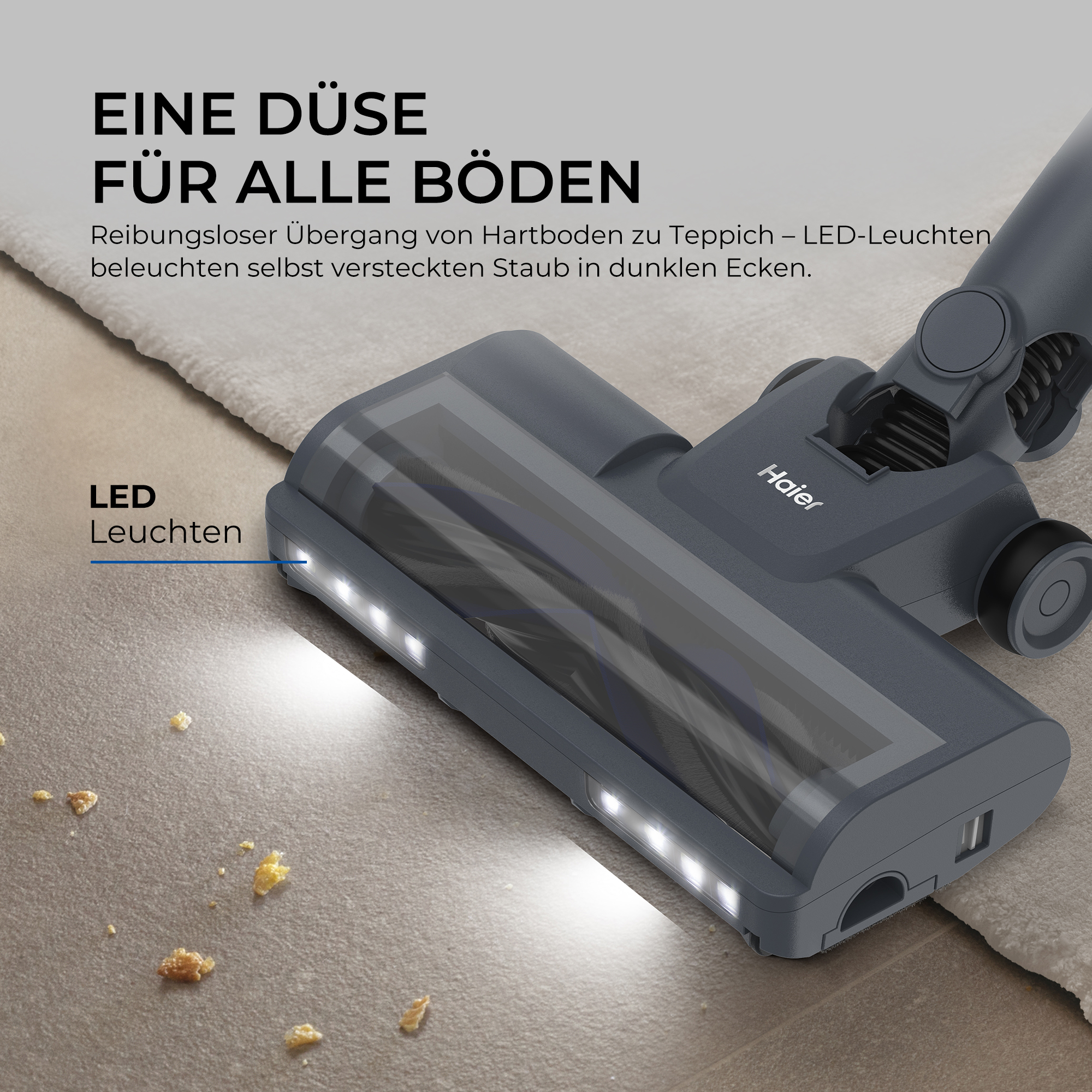 Eine Haier Staubsaugerdüse mit LED-Leuchten auf einem Teppich und Fliesenboden mit Krümeln.
