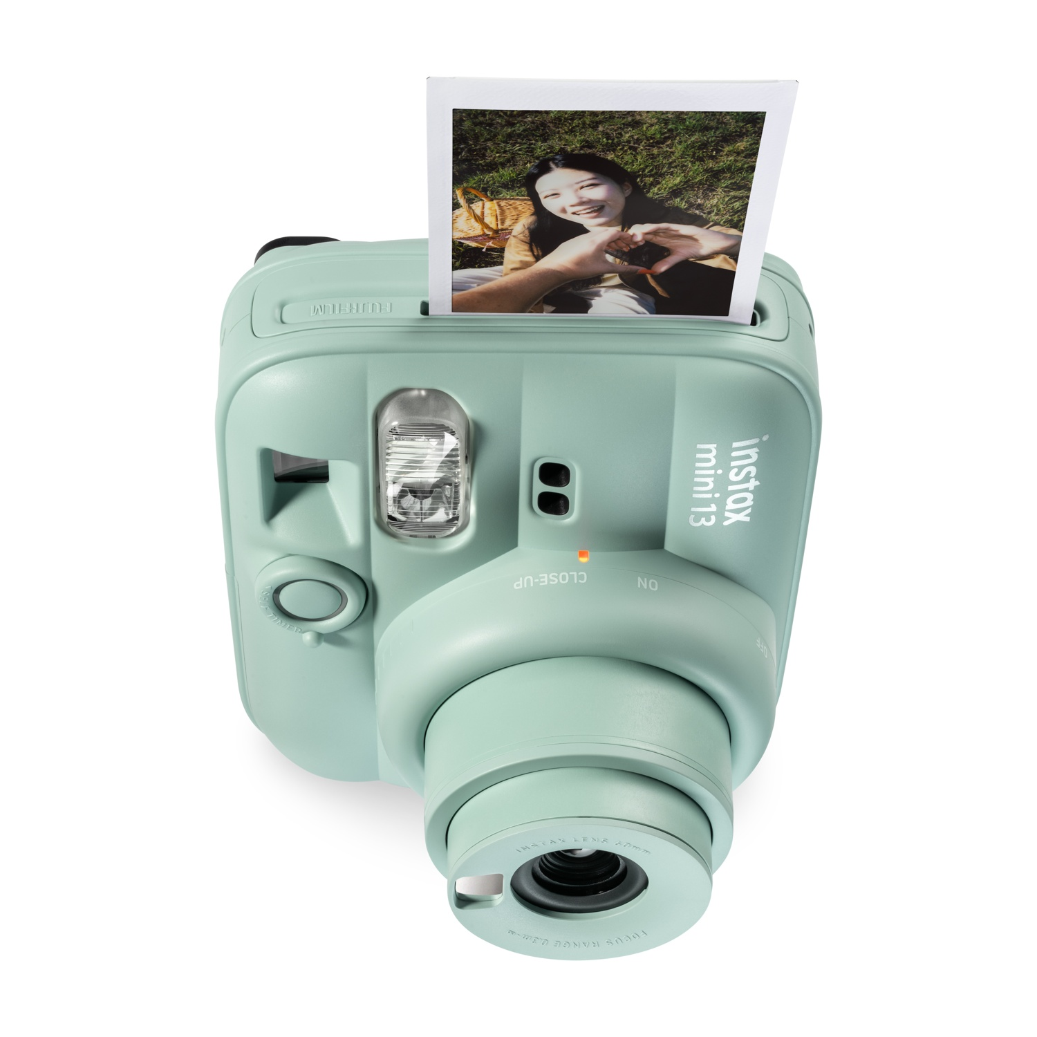 Una fotocamera istantanea verde menta con una foto che mostra una donna sorridente che fa un cuore.