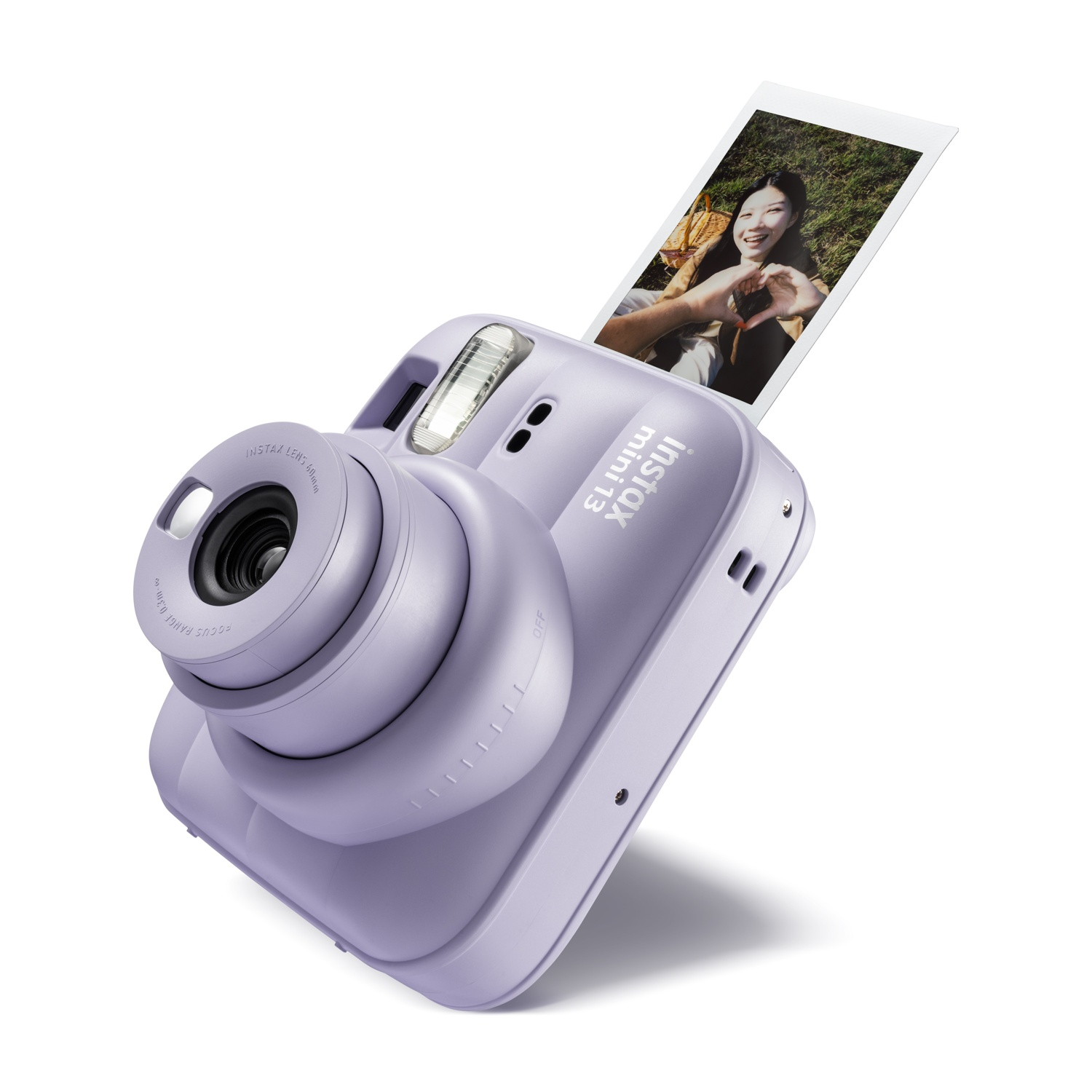 Una fotocamera Instax Mini 12 viola pastello espelle la foto stampata di una donna sorridente.