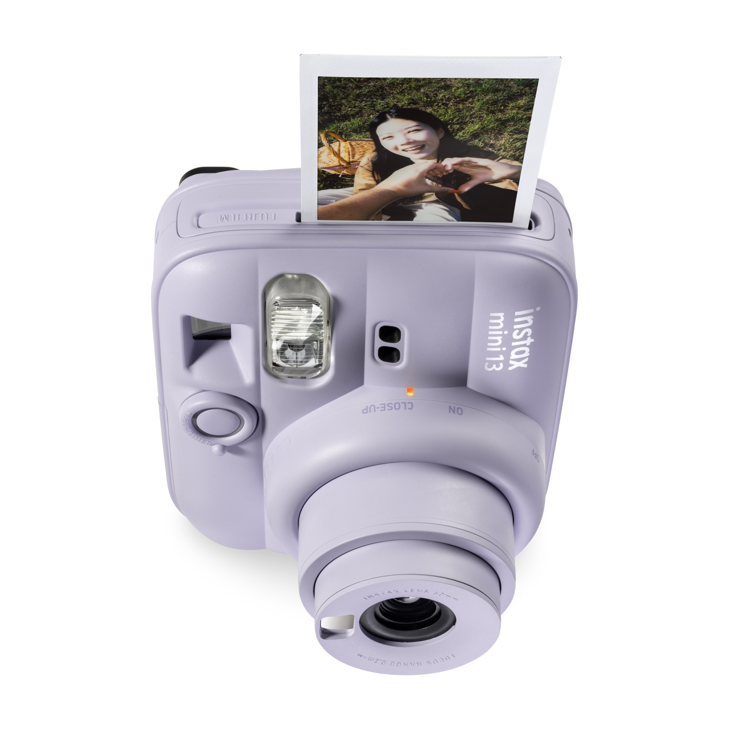 Fotocamera istantanea Instax Mini 13 viola con una foto stampata di una donna sopra, isolata su bianco.