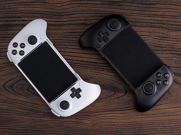 Ein weißer und ein schwarzer mobiler Gamecontroller auf einer Holztischoberfläche.