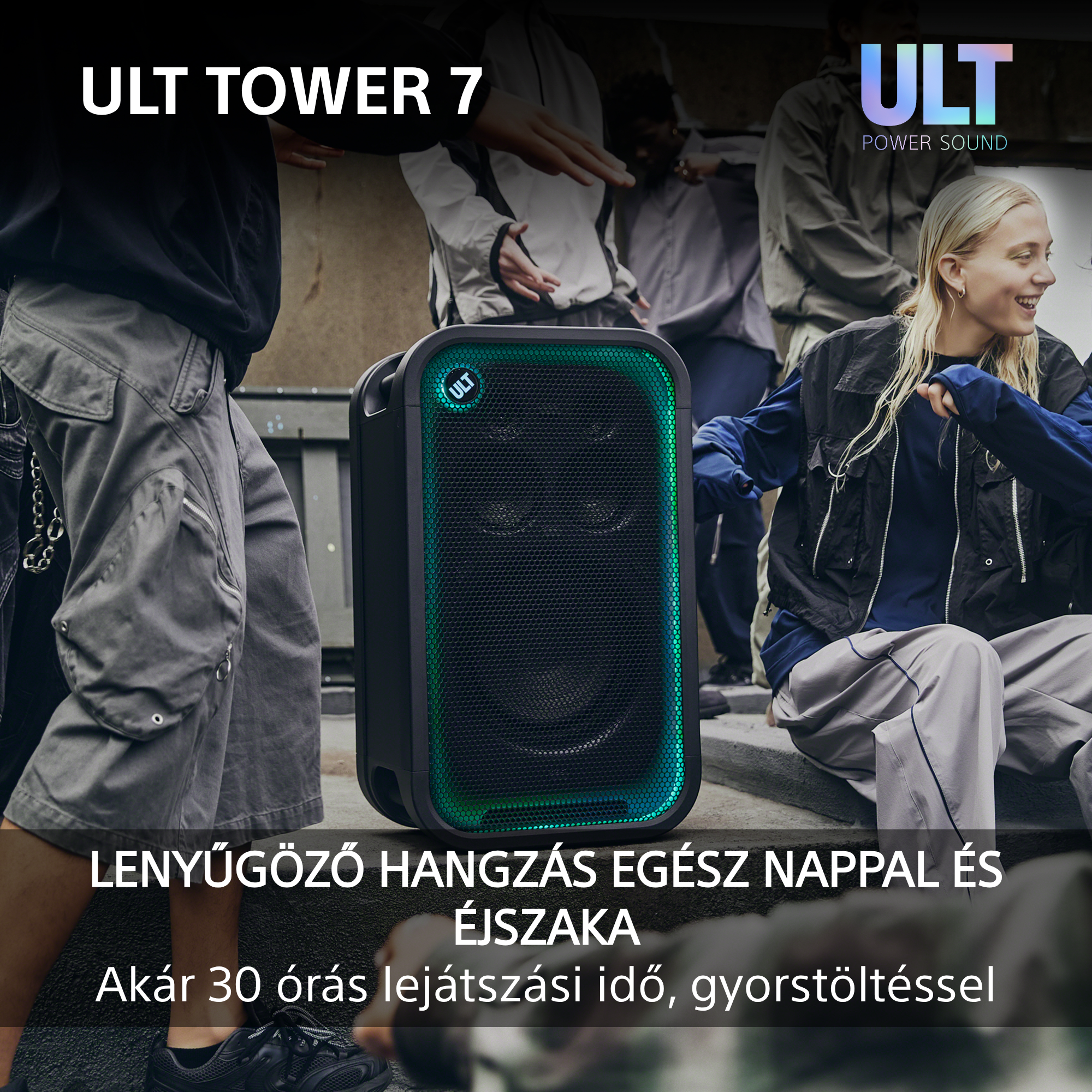 Egy ULT Tower 7 hangszóró zöld fénnyel világít, miközben fiatalok táncolnak a háttérben.