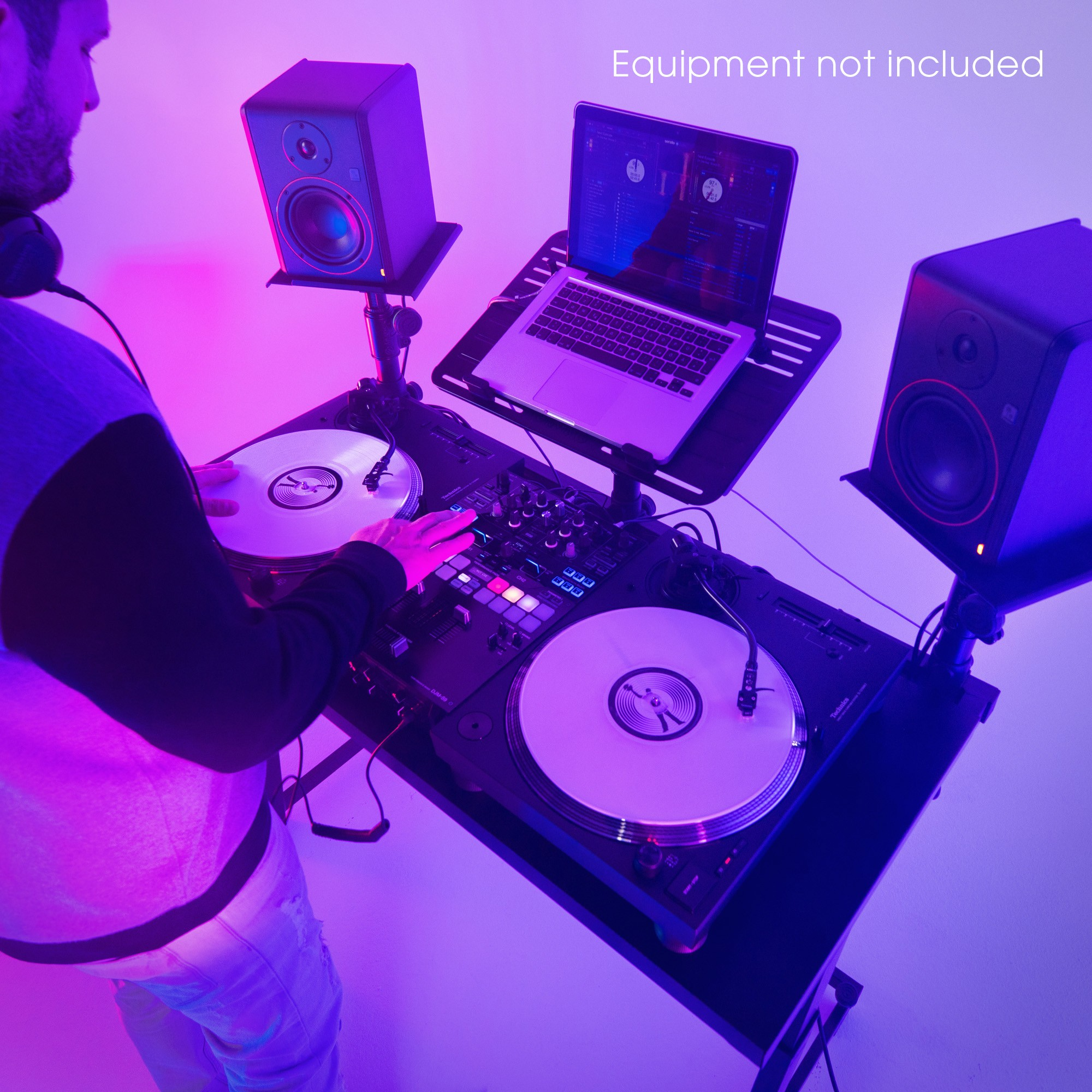 Un DJ mixant de la musique avec des platines, une table de mixage, un ordinateur et des moniteurs sous un éclairage rose et bleu.