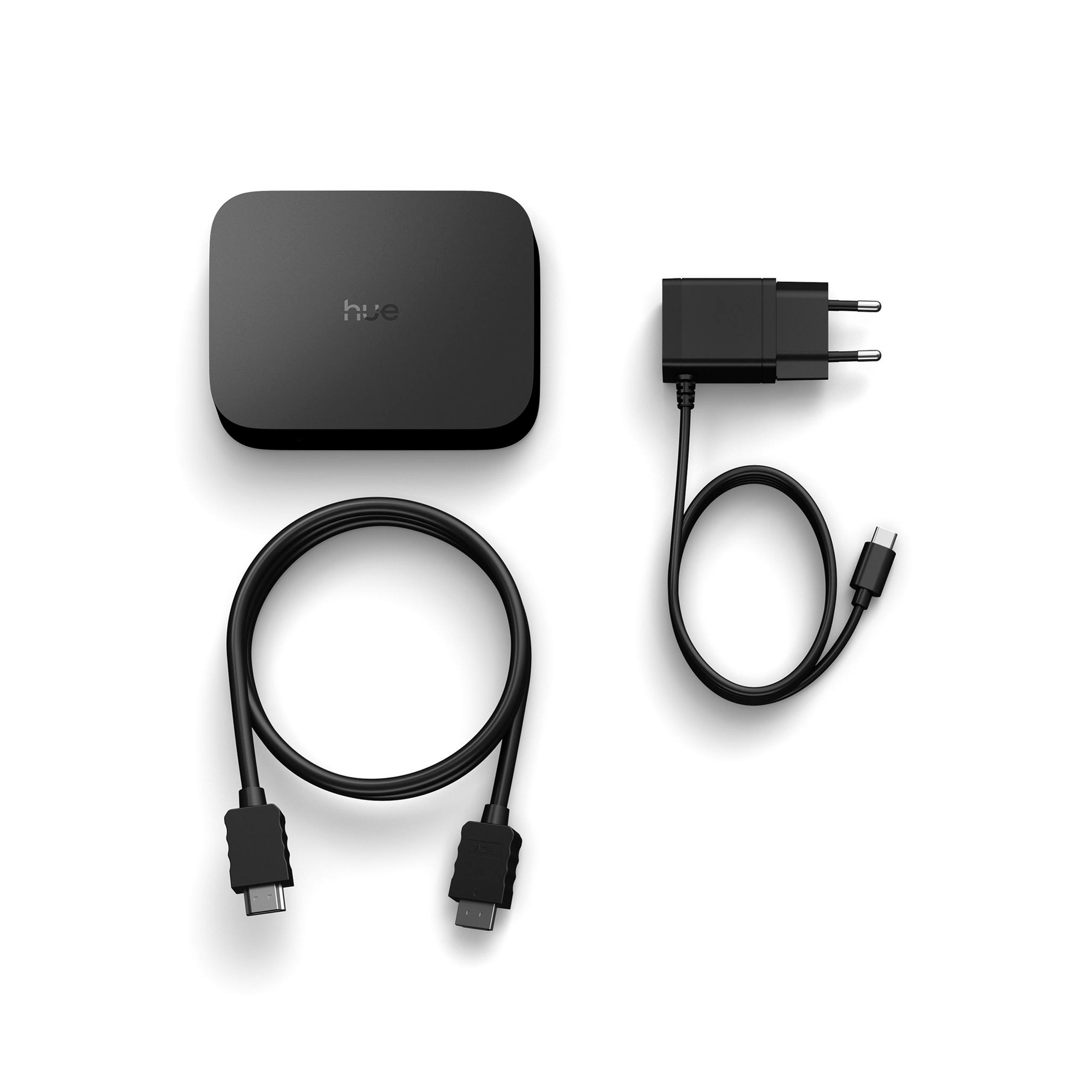 Eine schwarze Philips Hue Sync Box, ein HDMI-Kabel und ein USB-Netzteil auf weißem Hintergrund.