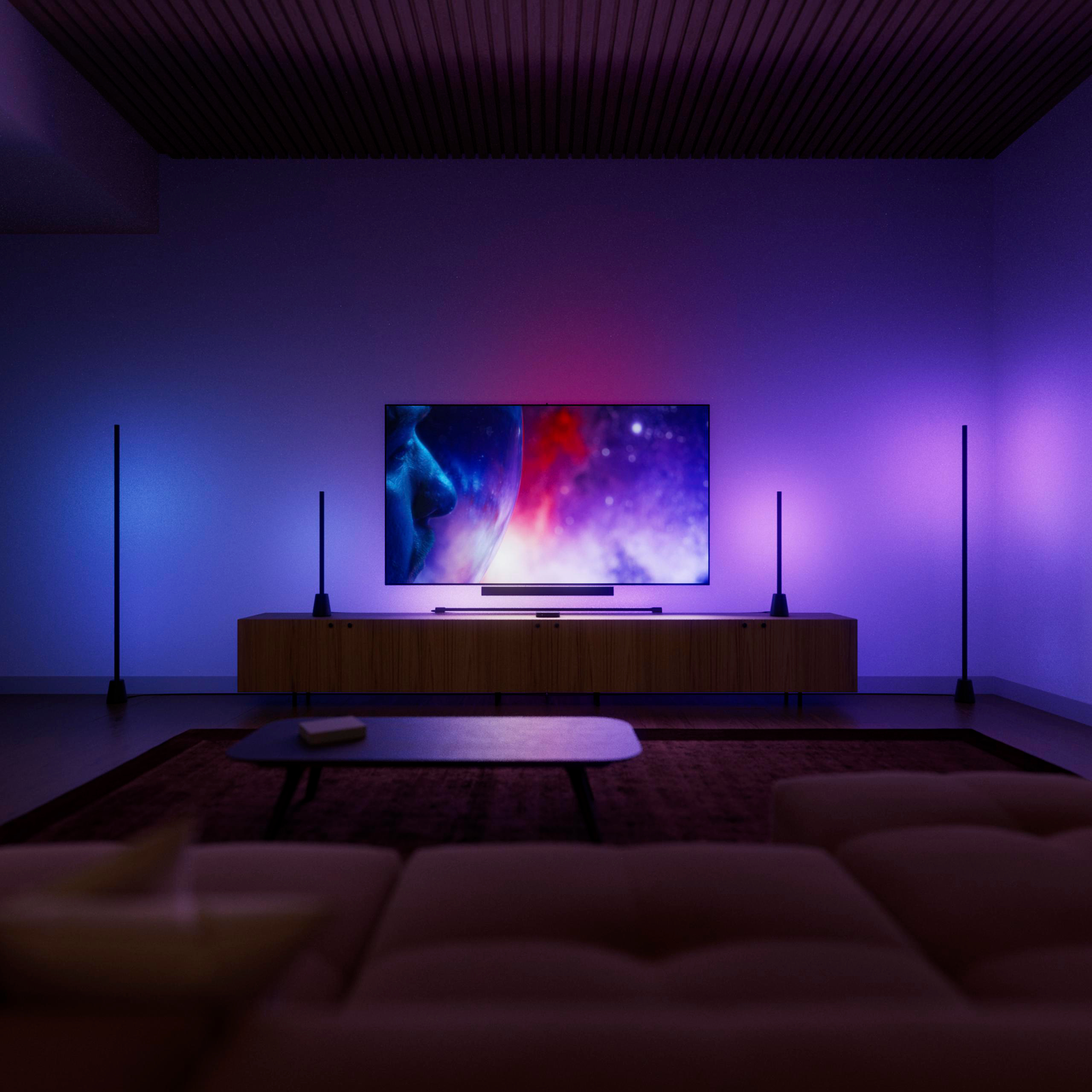 Wohnzimmer mit blauem und rotem Umgebungslicht, Fernseher auf einem Holzschrank und Couch im Vordergrund.