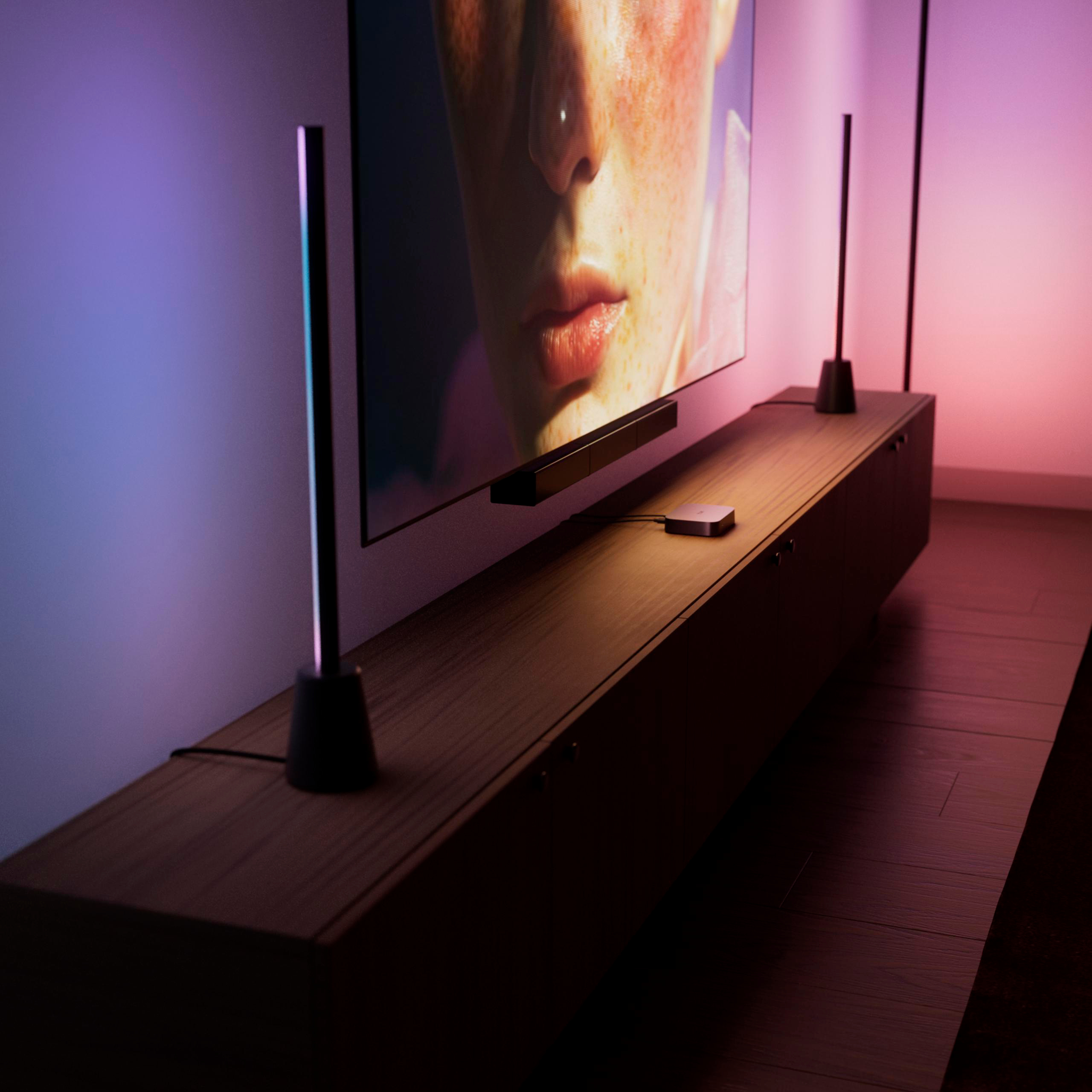 Ein langes Holzkastenelement mit einem grossen Fernseher und modernen Lampen an der Wand.