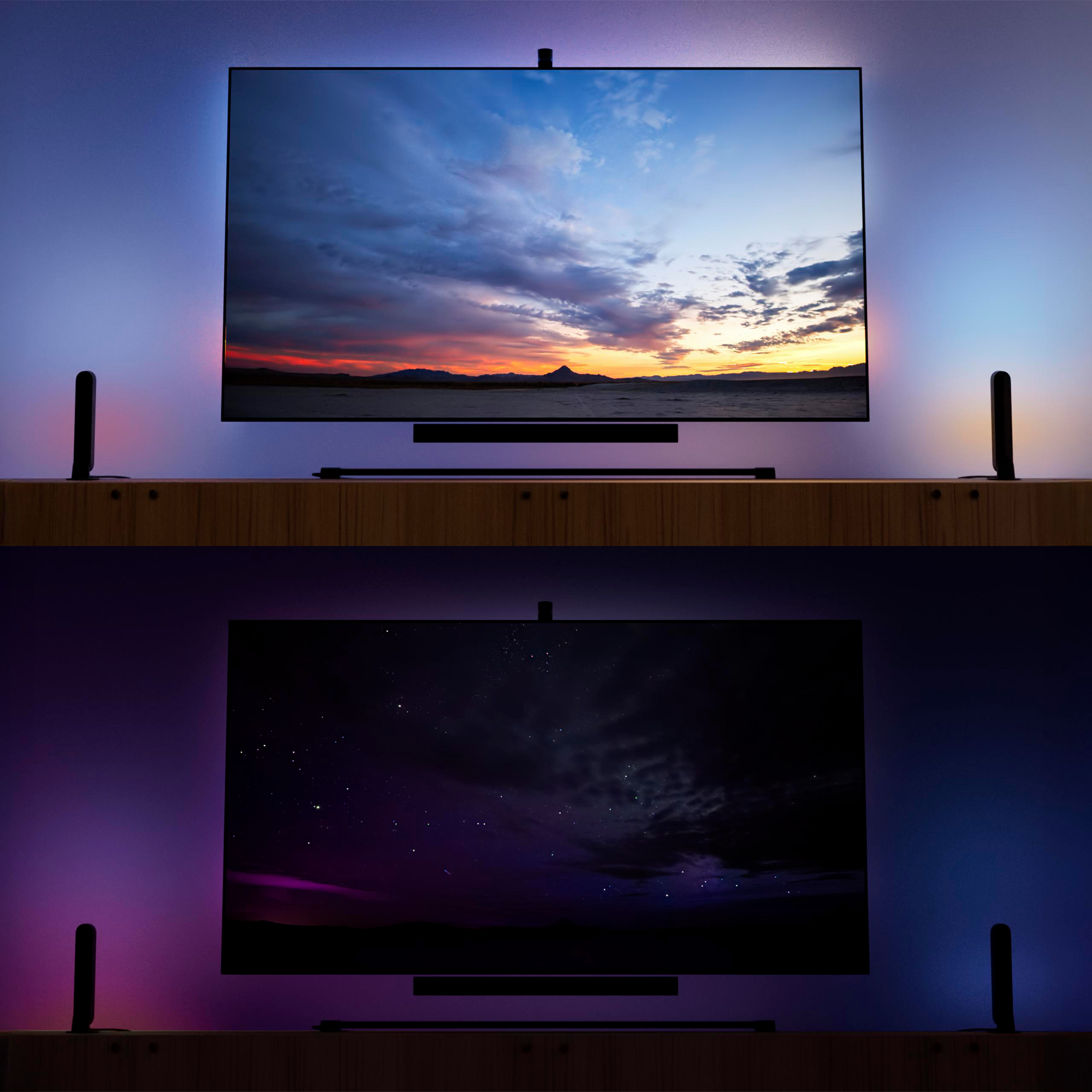 Zwei Fernseher auf Holzböden zeigen abwechselnd Sonnenuntergang und Nachthimmel mit stimmungsvoller Hintergrundbeleuchtung.