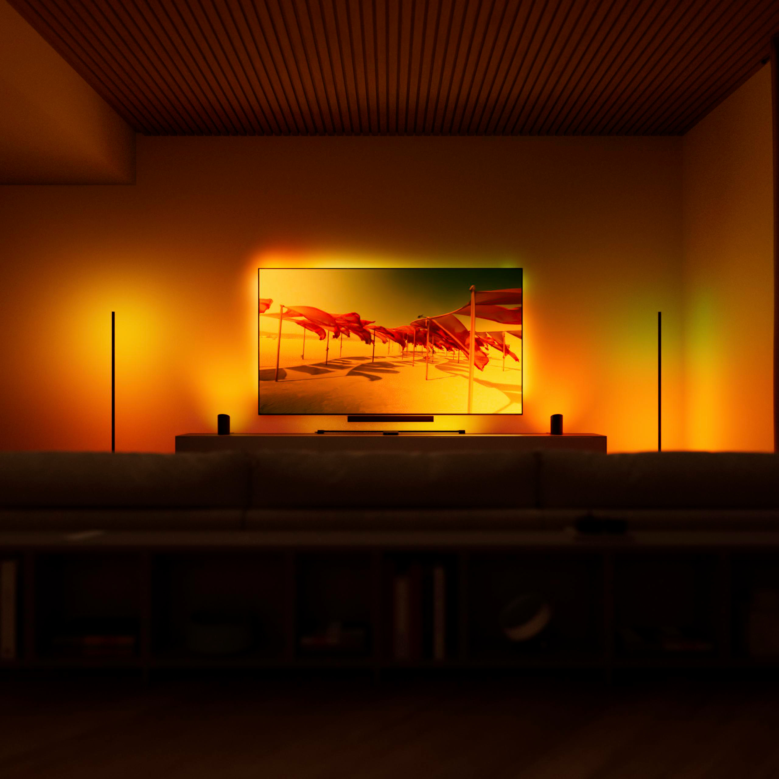 Ein beleuchteter Fernseher zeigt ein Strandbild mit roter Hintergrundbeleuchtung in einem dunklen Raum.