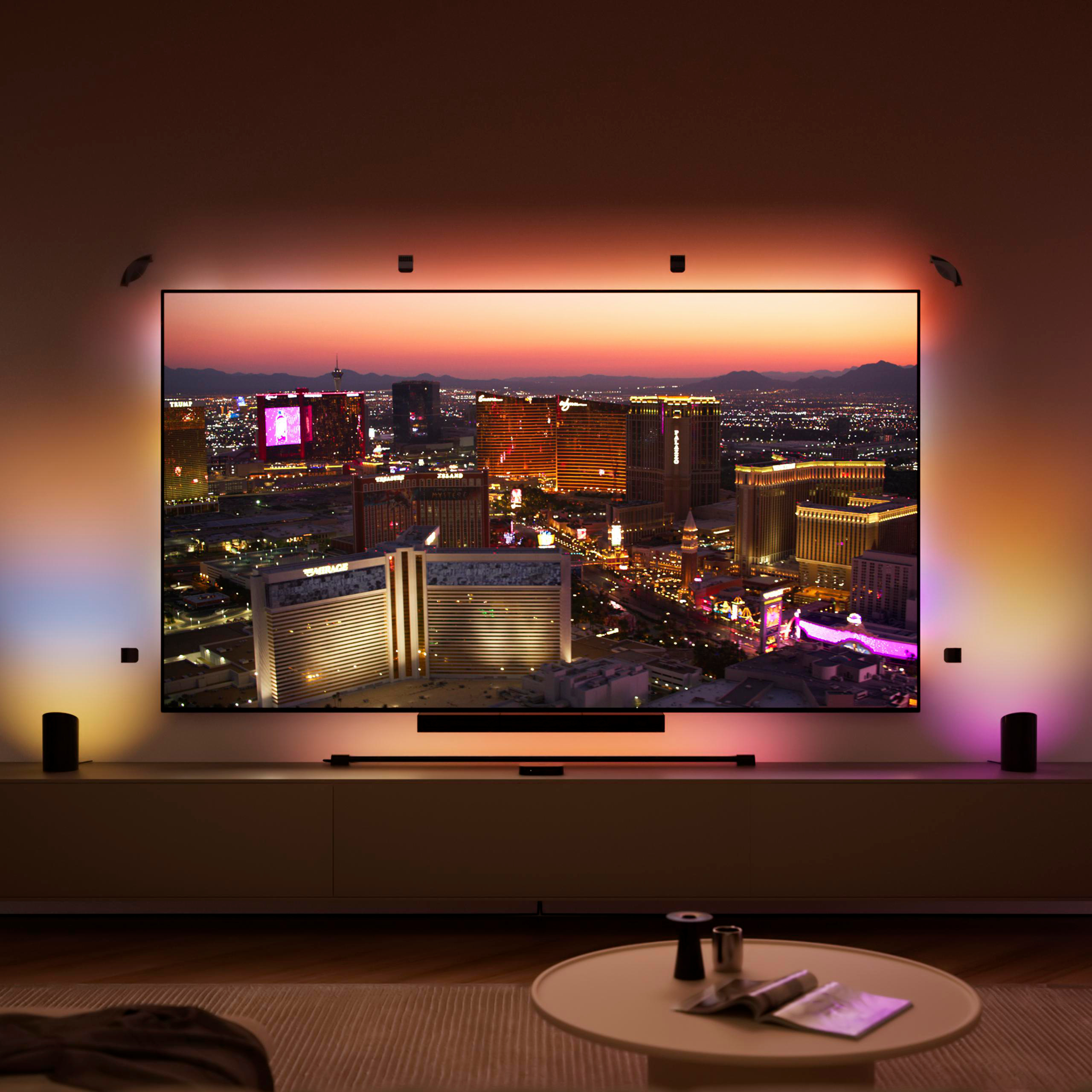 Ein großer Fernseher an einer Wand zeigt eine abendliche Stadtlandschaft mit warmem, umgebendem LED-Licht.