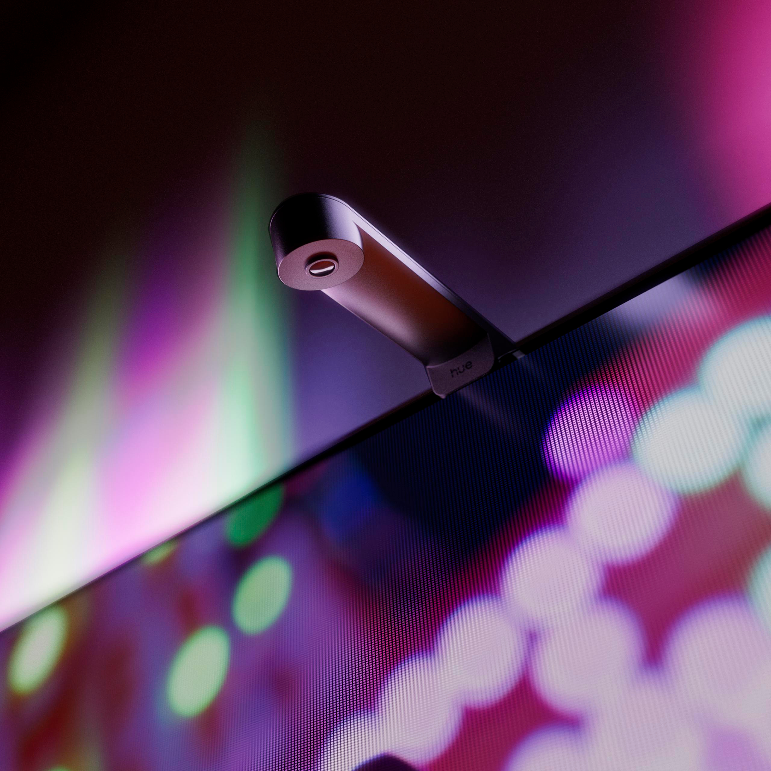 Eine Philips Hue Play HDMI Sync Box Kamera montiert auf einem Bildschirm mit farbigem Hintergrundlicht.