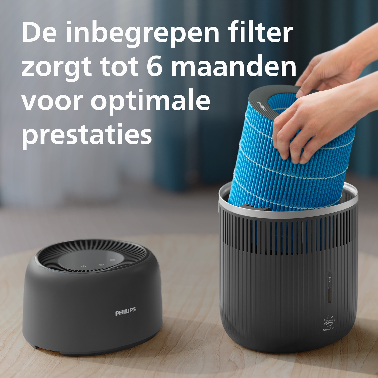 Een blauwe filter wordt door handen in een grijze luchtbevochtiger op een houten tafel geplaatst.
