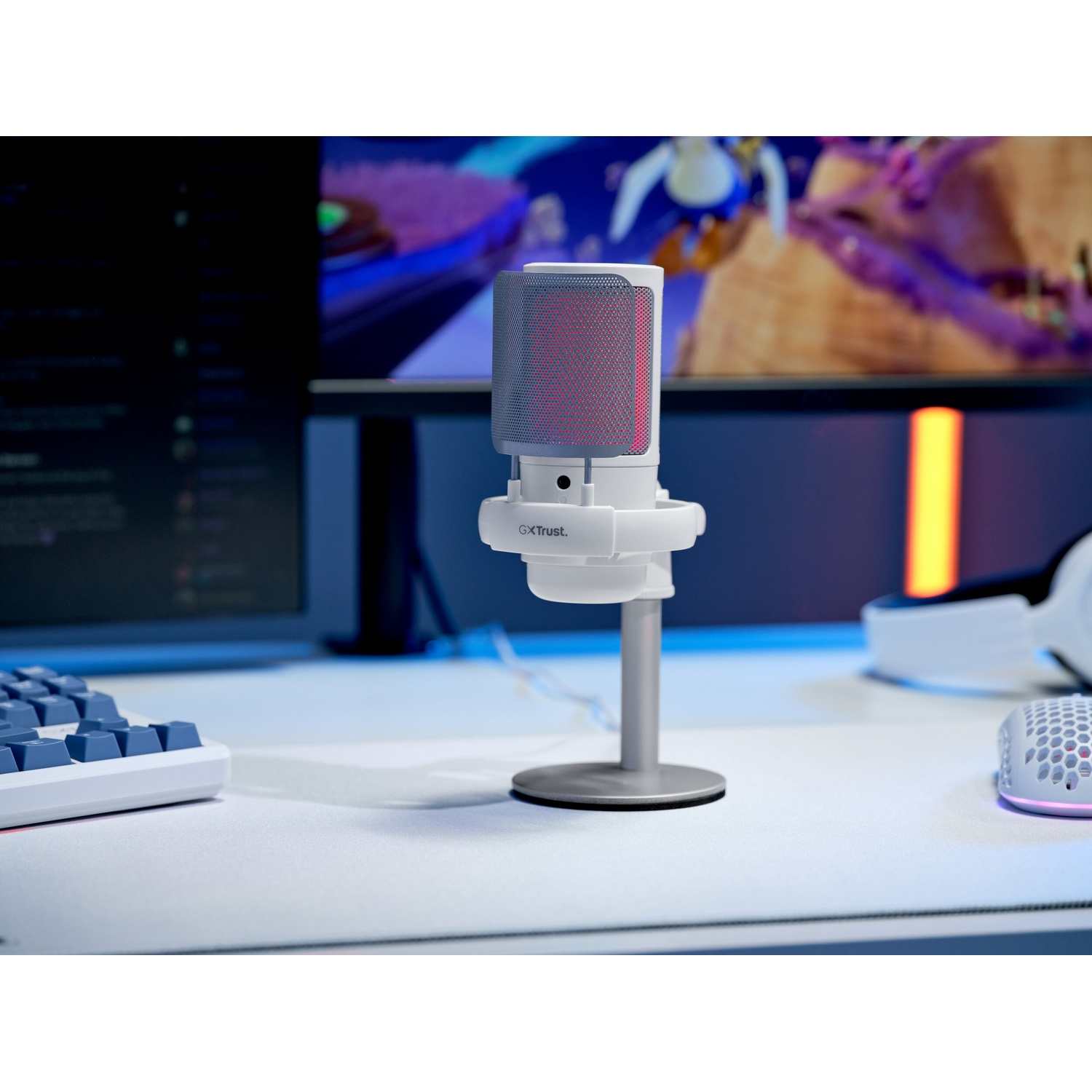 Un microfono GXT bianco su supporto davanti a un monitor.