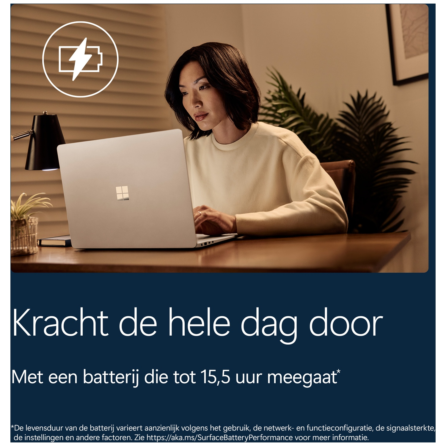 Een vrouw typt op een laptop aan een houten bureau, met een lamp en planten op de achtergrond.