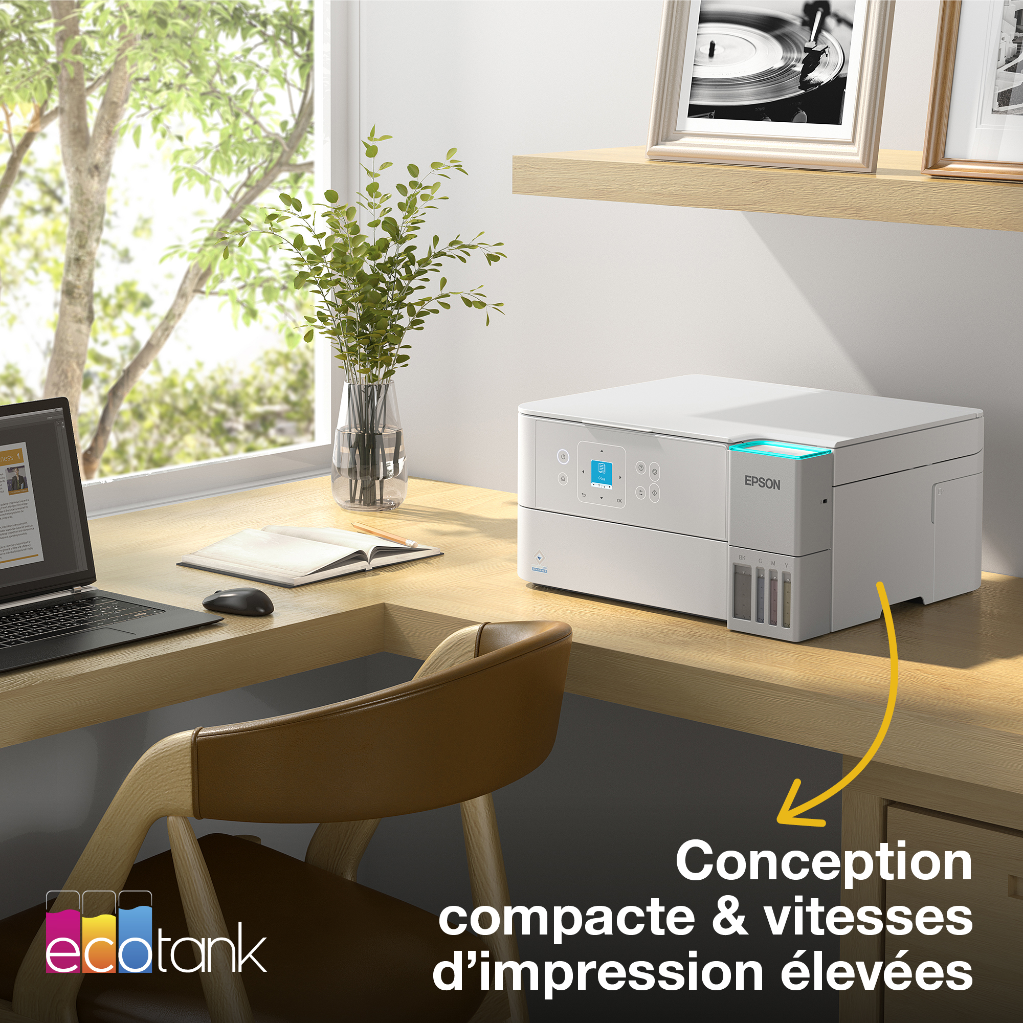 Une imprimante blanche Epson EcoTank sur un bureau en bois à côté d'une plante et d'un ordinateur.