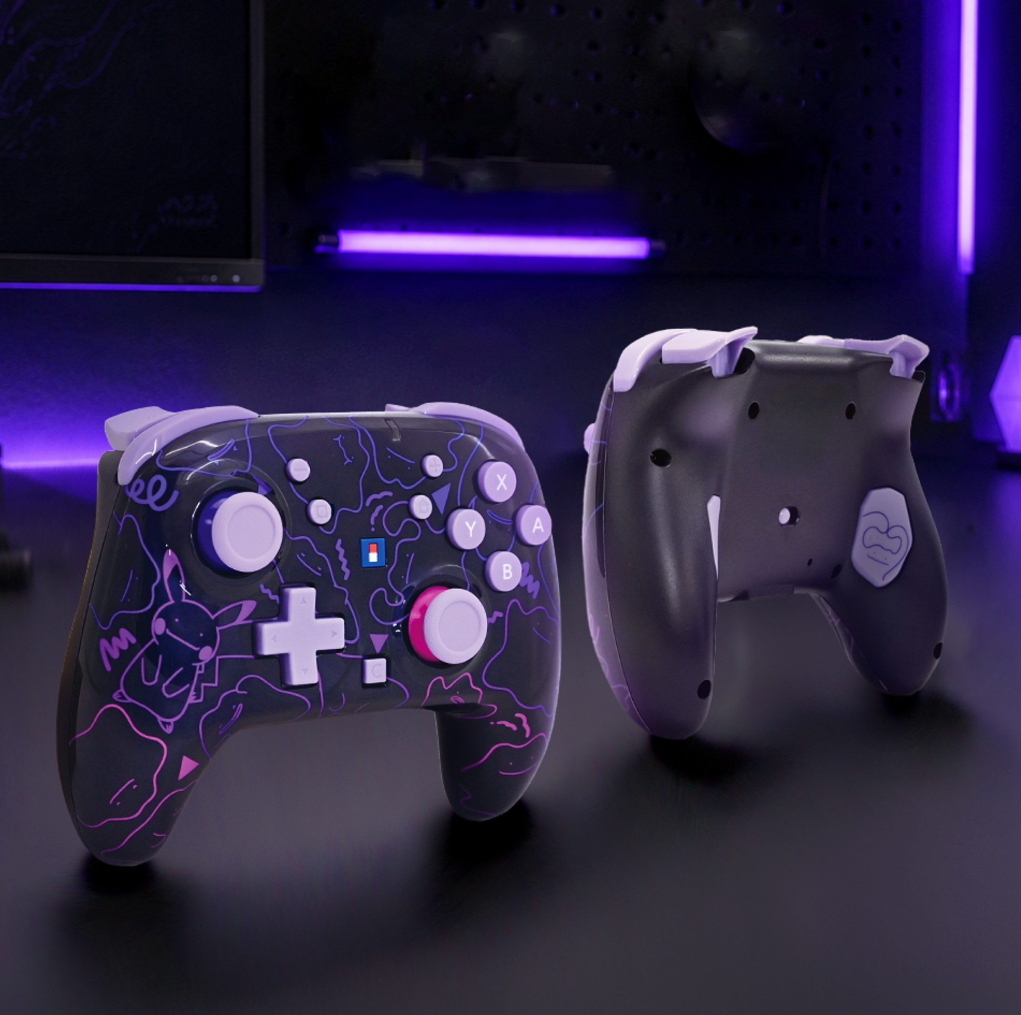 Zwei schwarze Gaming-Controller mit lila Akzenten und Pokémon-Motiven stehen auf einem Tisch vor blauem Licht.